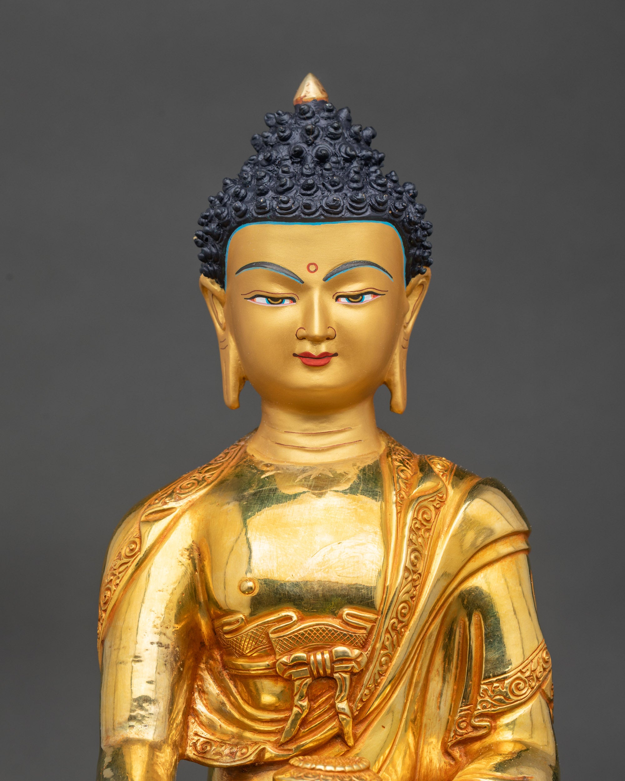 Close-up of Buddha face showing serene expression and intricate gilded copper details