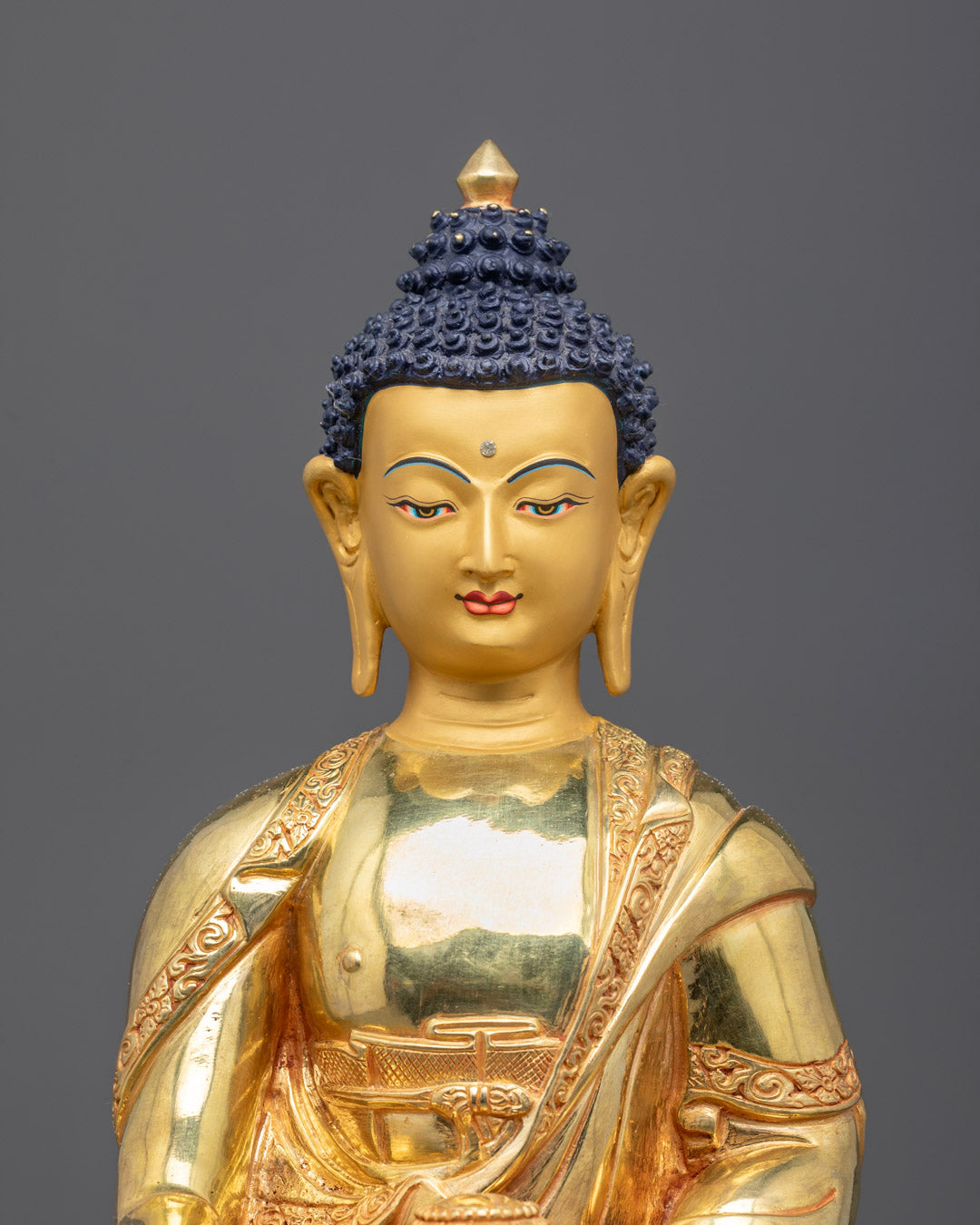 Close-up of Buddha statue’s serene face adorned with gold and delicate craftsmanship.