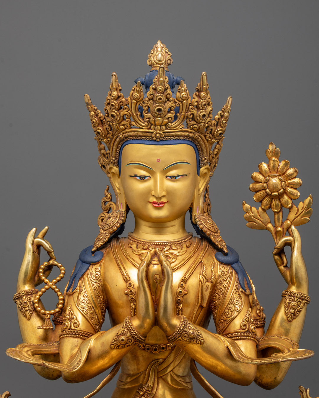Close-up of Chenrezig’s serene face and hands holding vajra and bell
