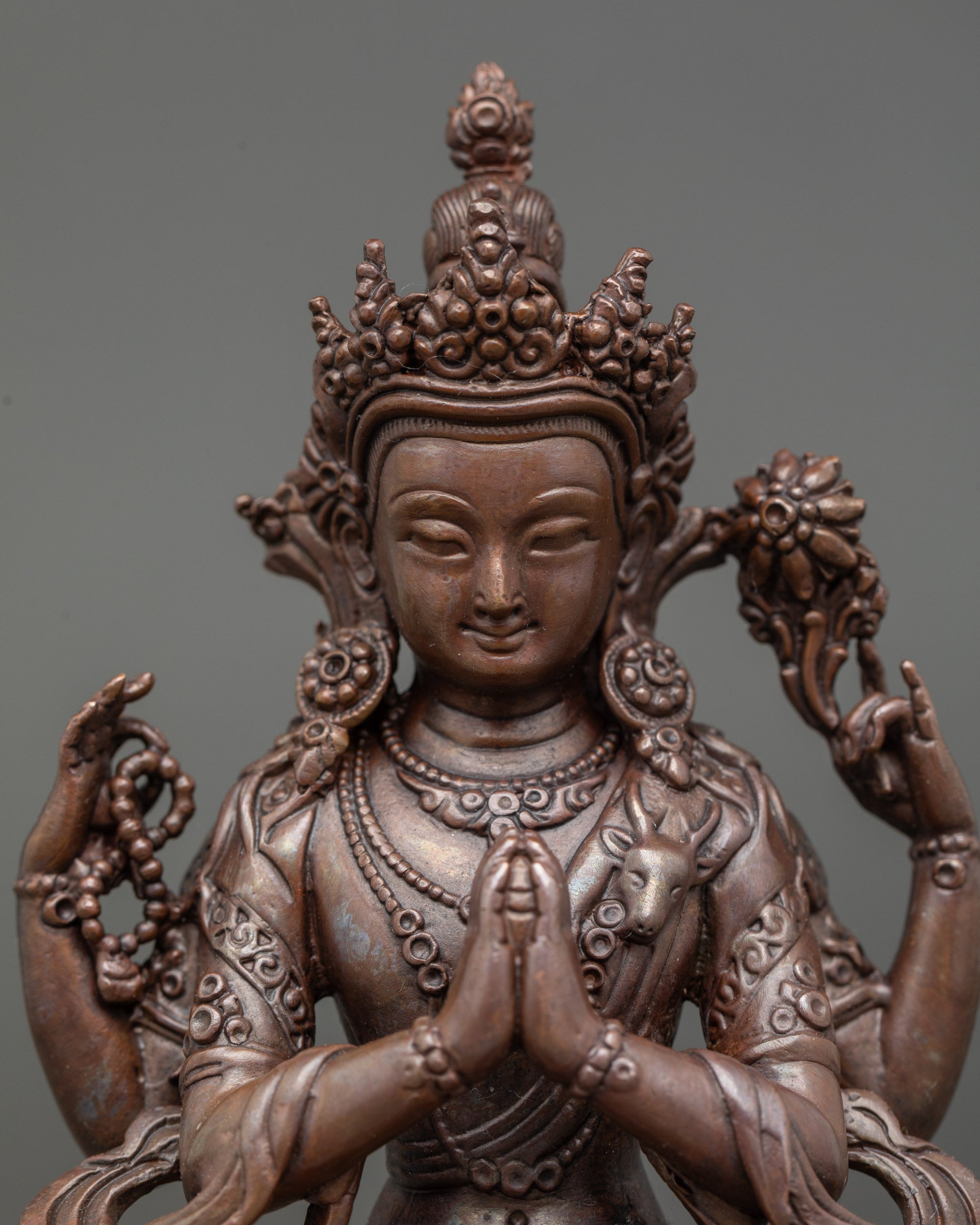Close-up of Chenrezig statue hands holding wish-fulfilling gem and crystal rosary