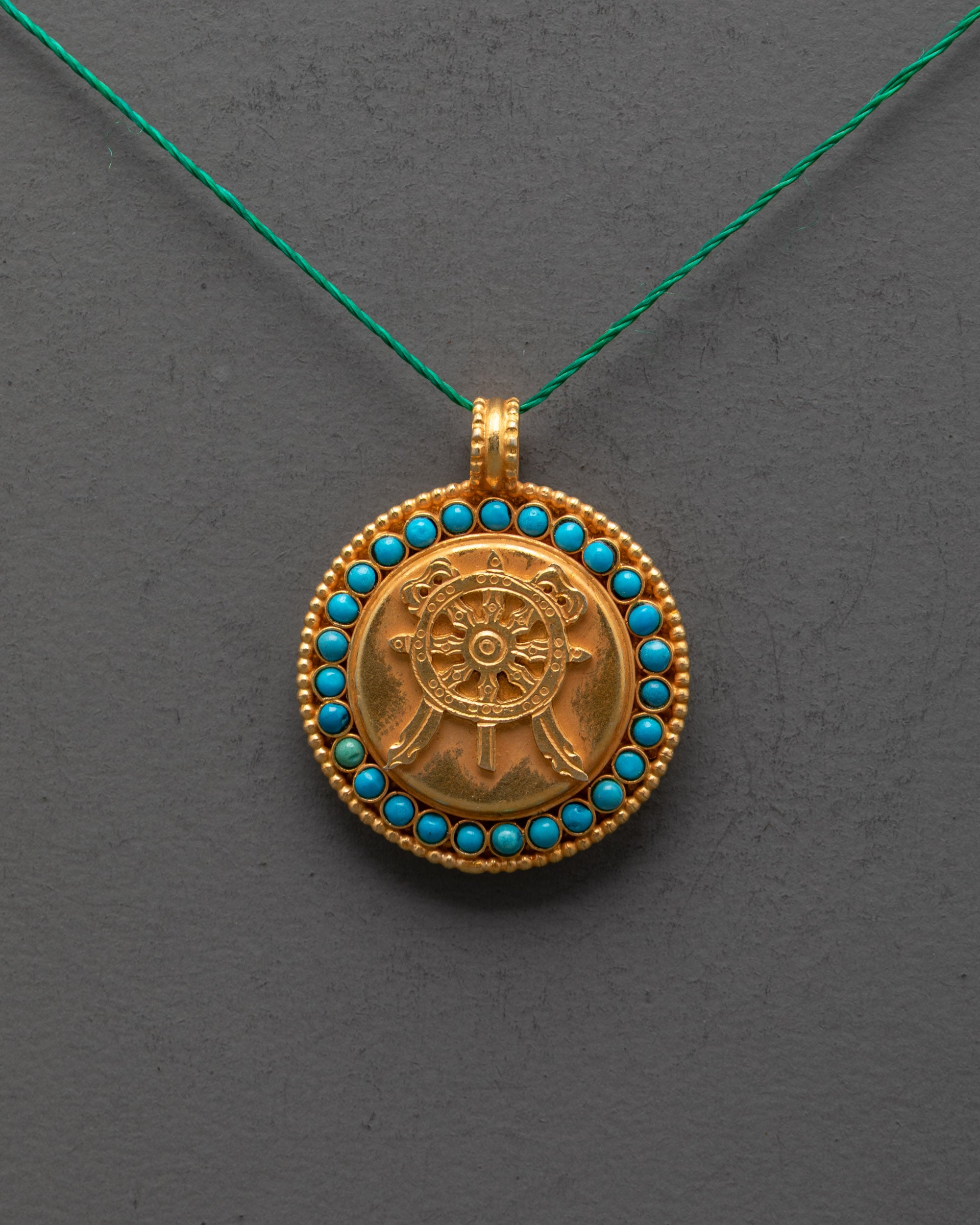 Close-up of Dharma Wheel Locket showing detailed carving and gemstone inlay