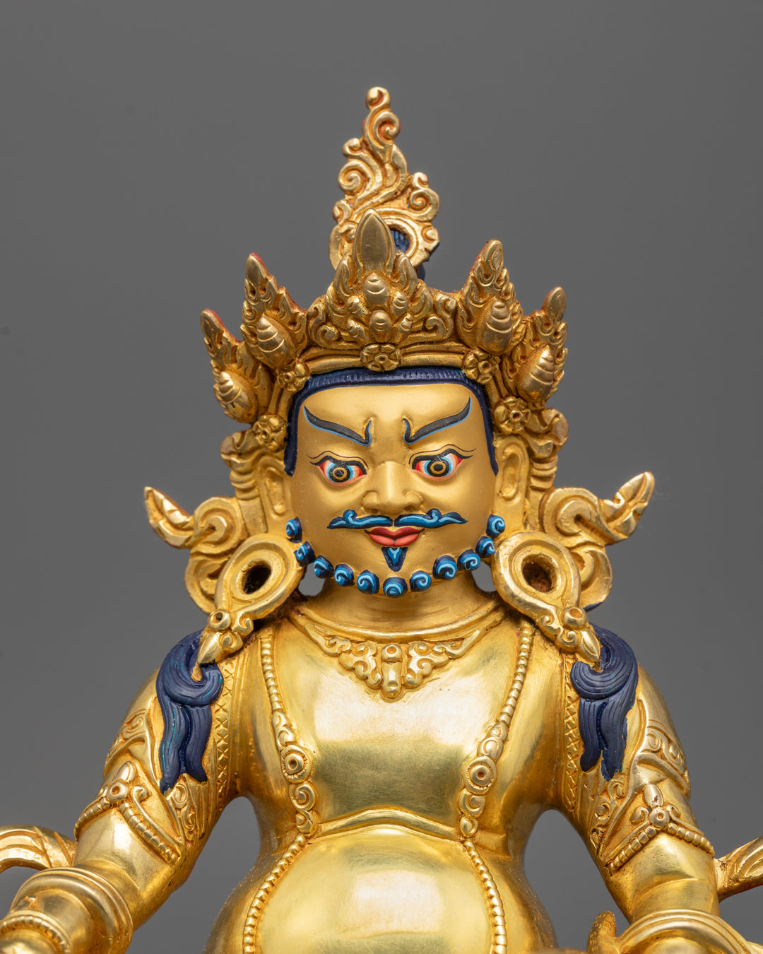 Close-up of Dzambhala's radiant face gilded in 24k gold holding a jewel-spouting mongoose