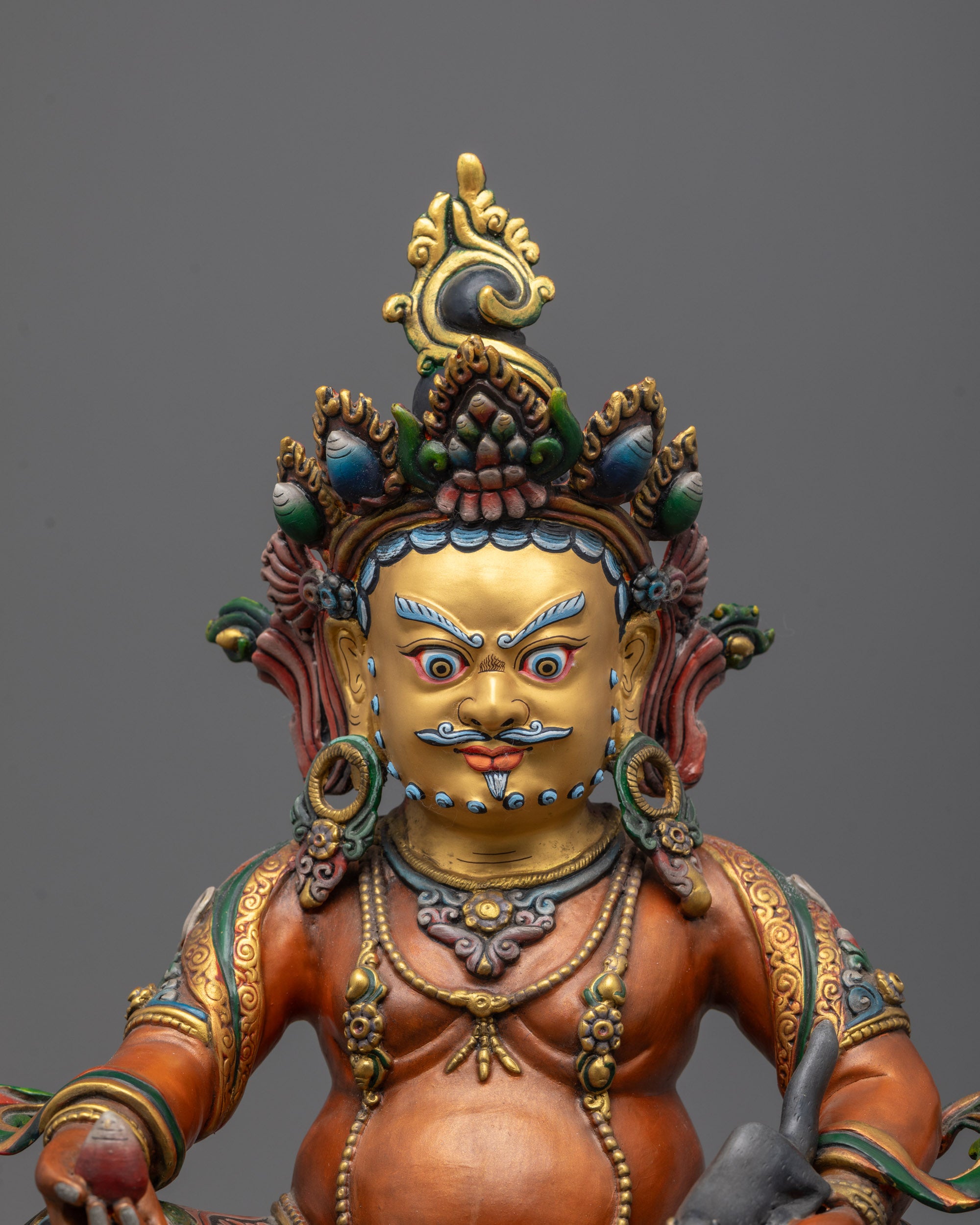 Close-up of Dzambhala’s radiant gold face and intricate copper detailing