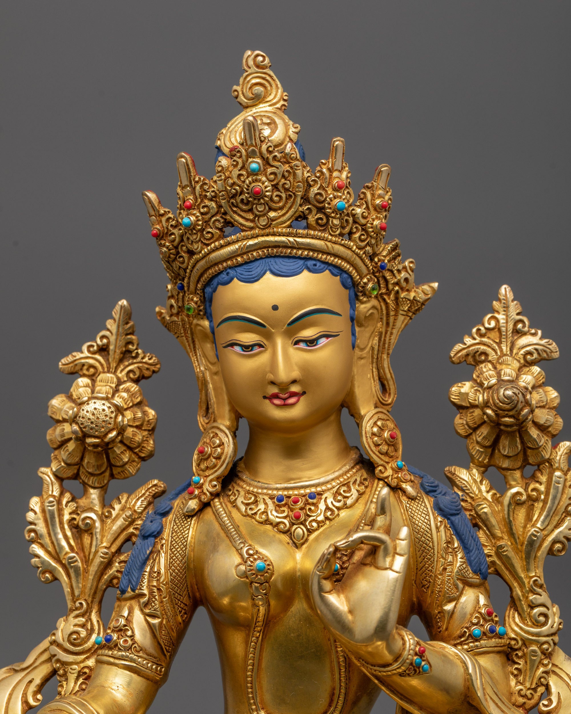 Gold-colored statue with intricate details on a dark background