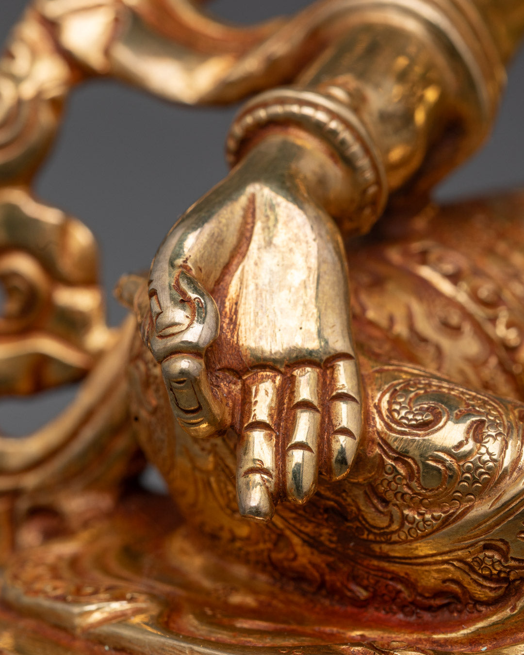 Green Tara’s compassionate face on a hand-carved copper statue with gold leaf and colorful acrylic paint accents.