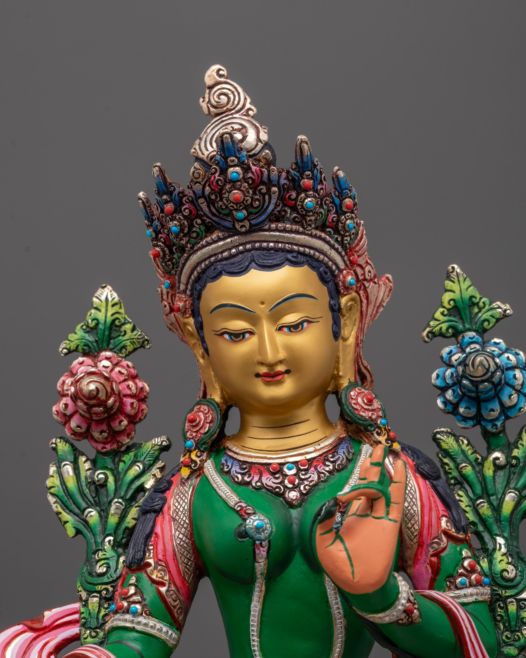 Close-up of Green Tara’s meditative face and varada mudra hand gesture on copper statue
