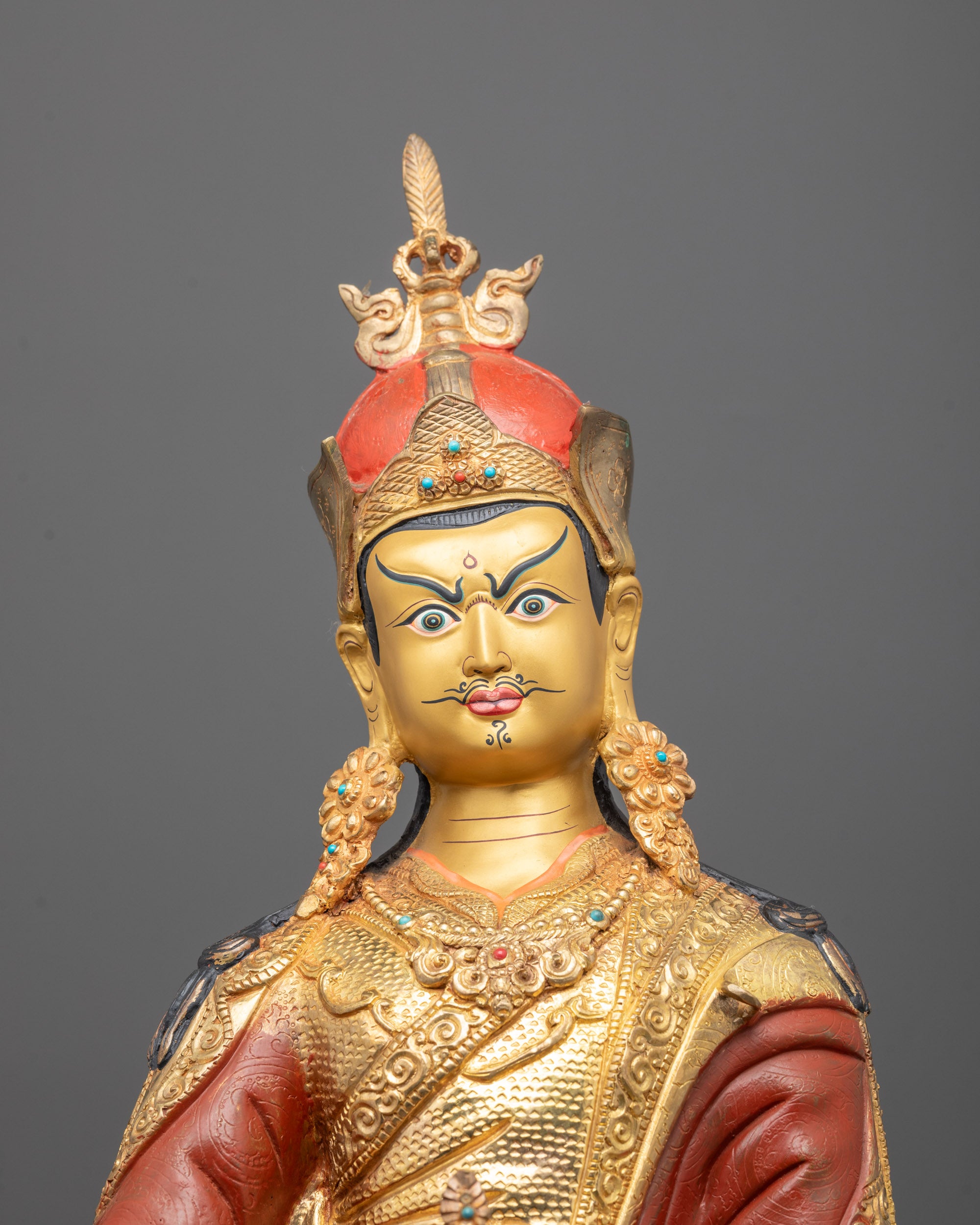 Close-up of Guru Rinpoche face showing intricate detailing and radiant gold-polished