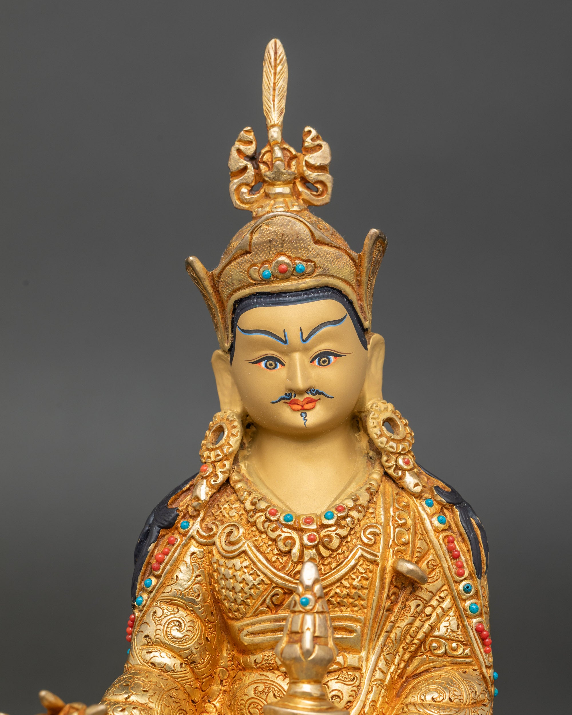 Close-up of Guru Rinpoche face showing serene gold-painted features, radiant 24K gilding, and exquisite Nepalese craftsmanship.