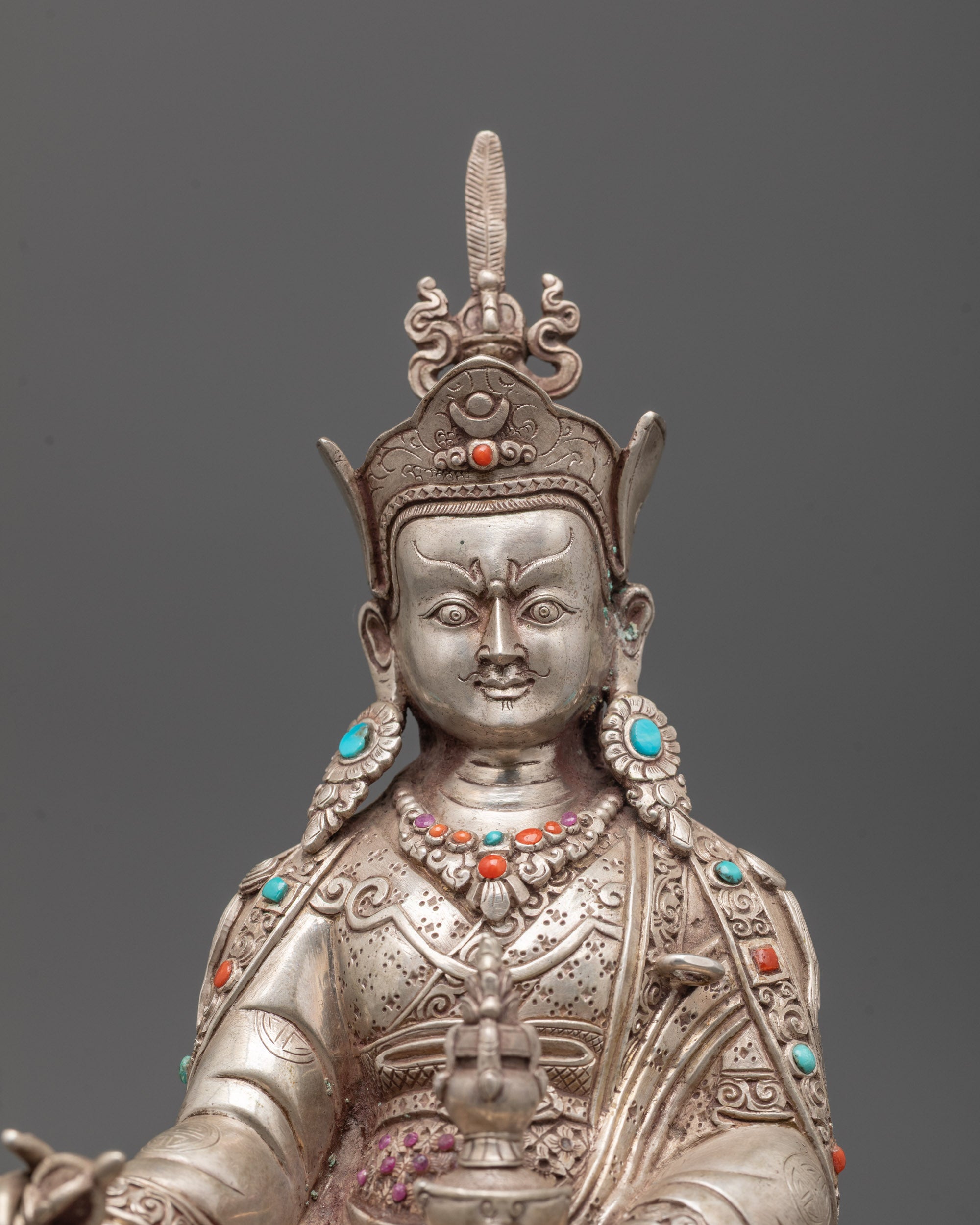 Close-up of Guru Rinpoche face showing silver detailing and crown carvings from lost wax method