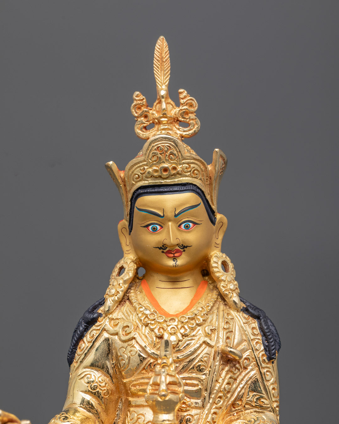 Close-up of Guru Rinpoche face with gold detailing and semi-precious stones
