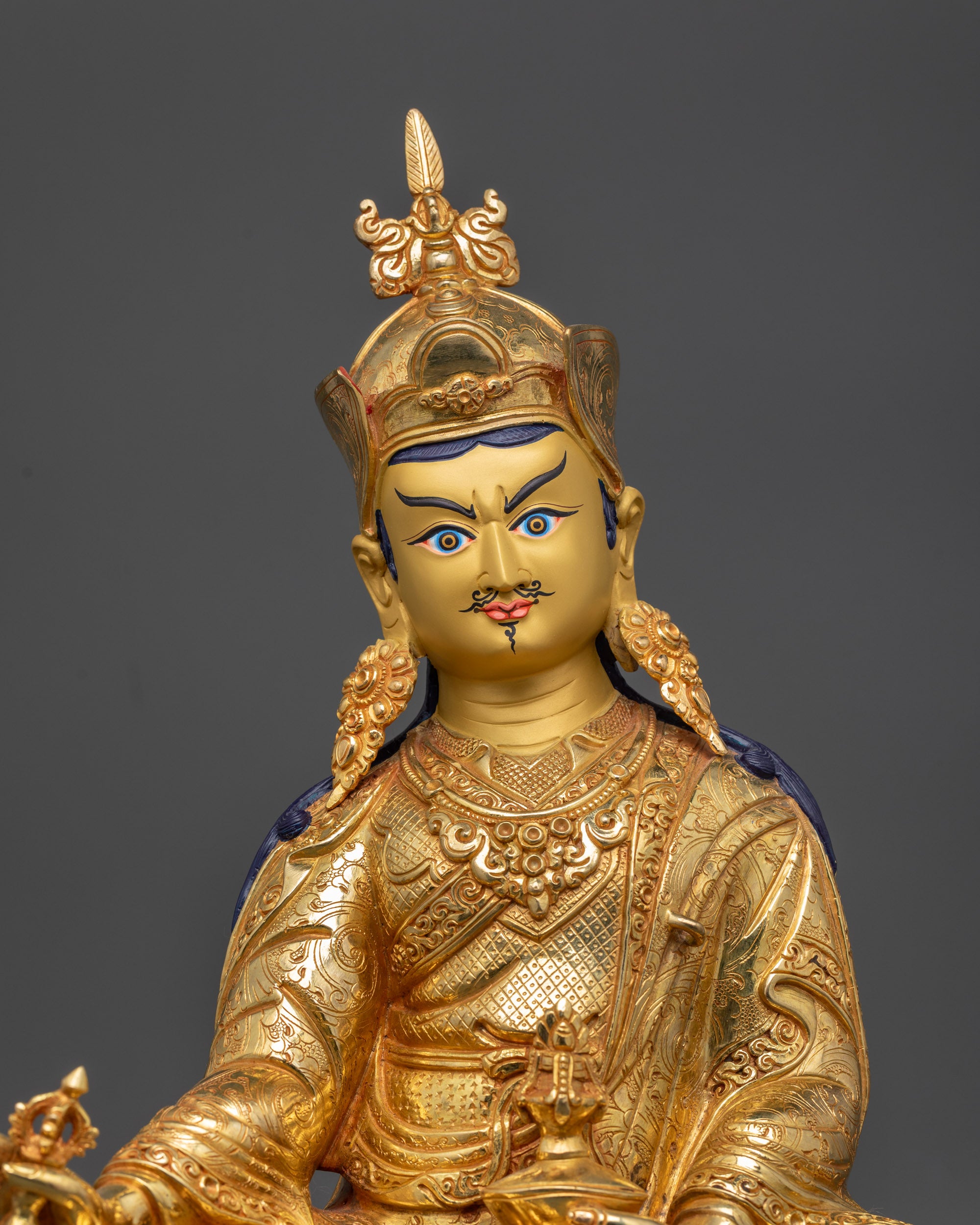 Close-up of Guru Rinpoche gold-gilded face showing wrathful yet compassionate expression