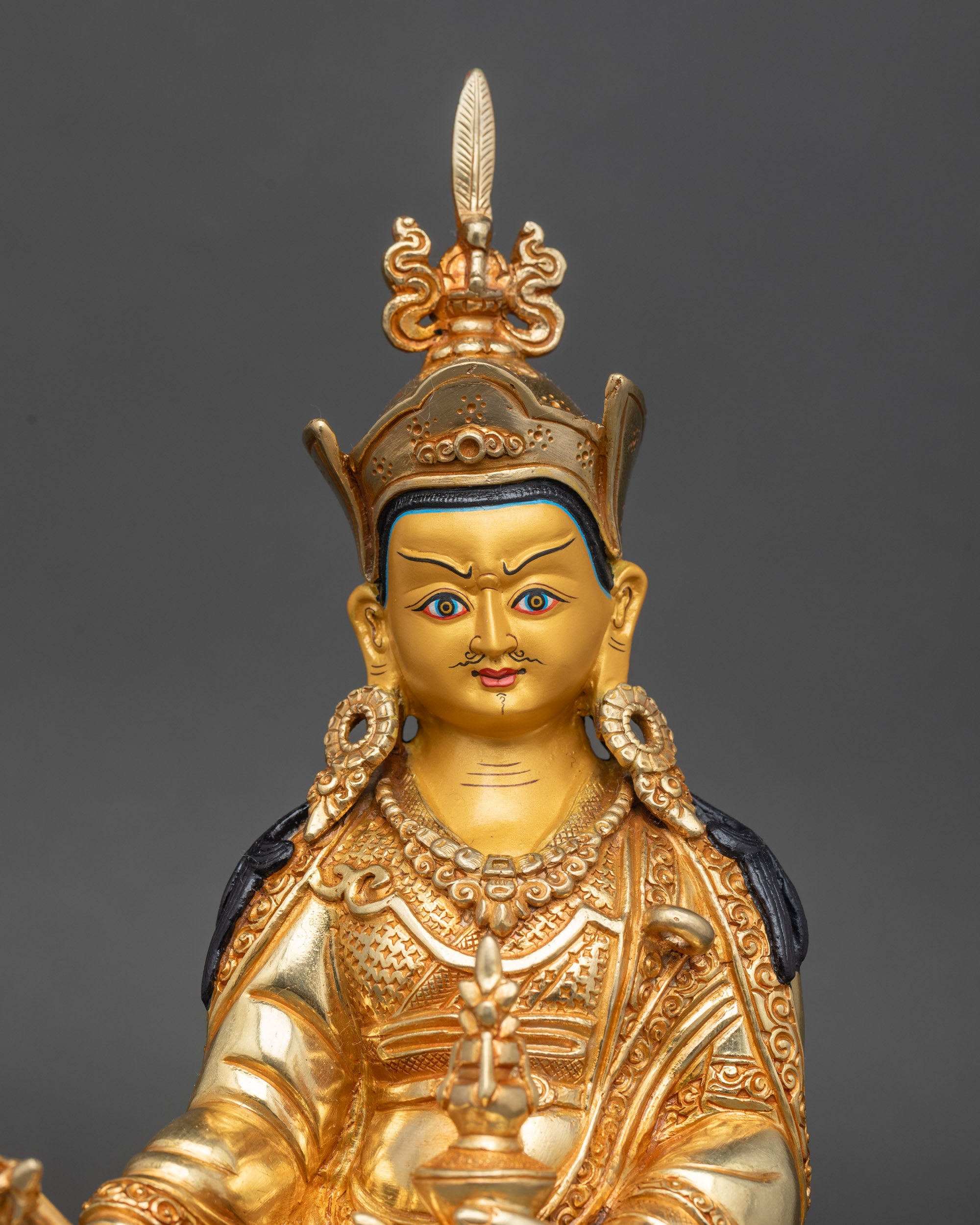 Close-up of Guru Rinpoche gold-painted face showing serene expression