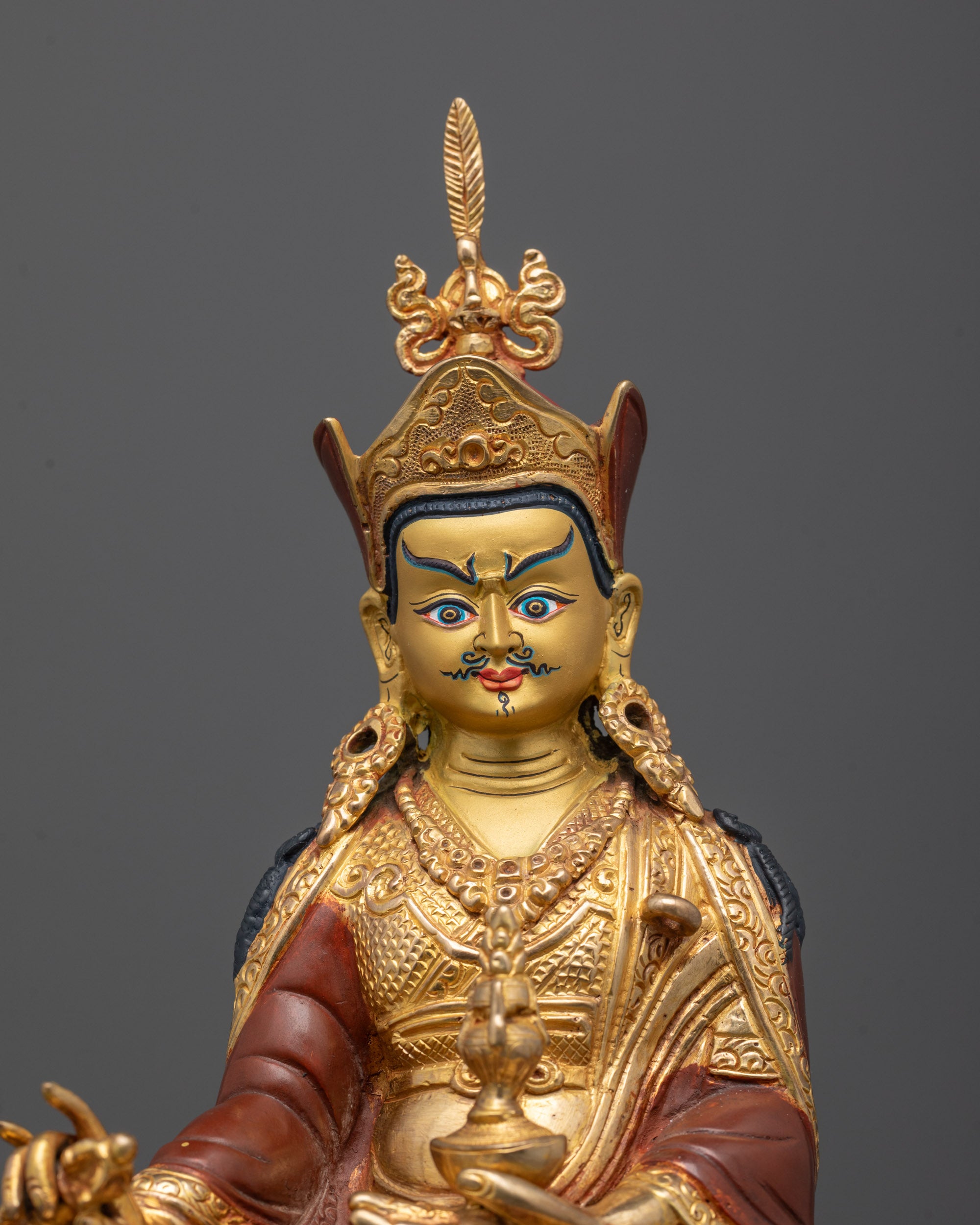 Close-up of Guru Rinpoche’s face, lotus hat, and intricately carved sacred halo