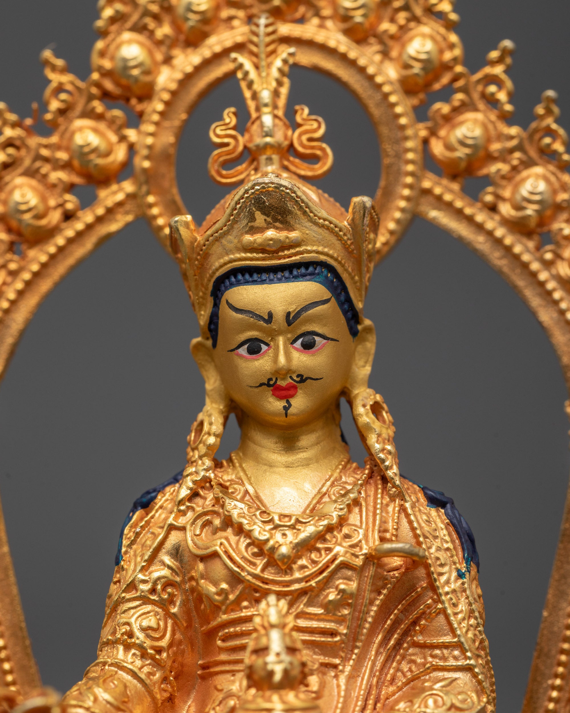 Close-up of Guru Rinpoche’s peaceful face and detailed 24k gold gilded copper