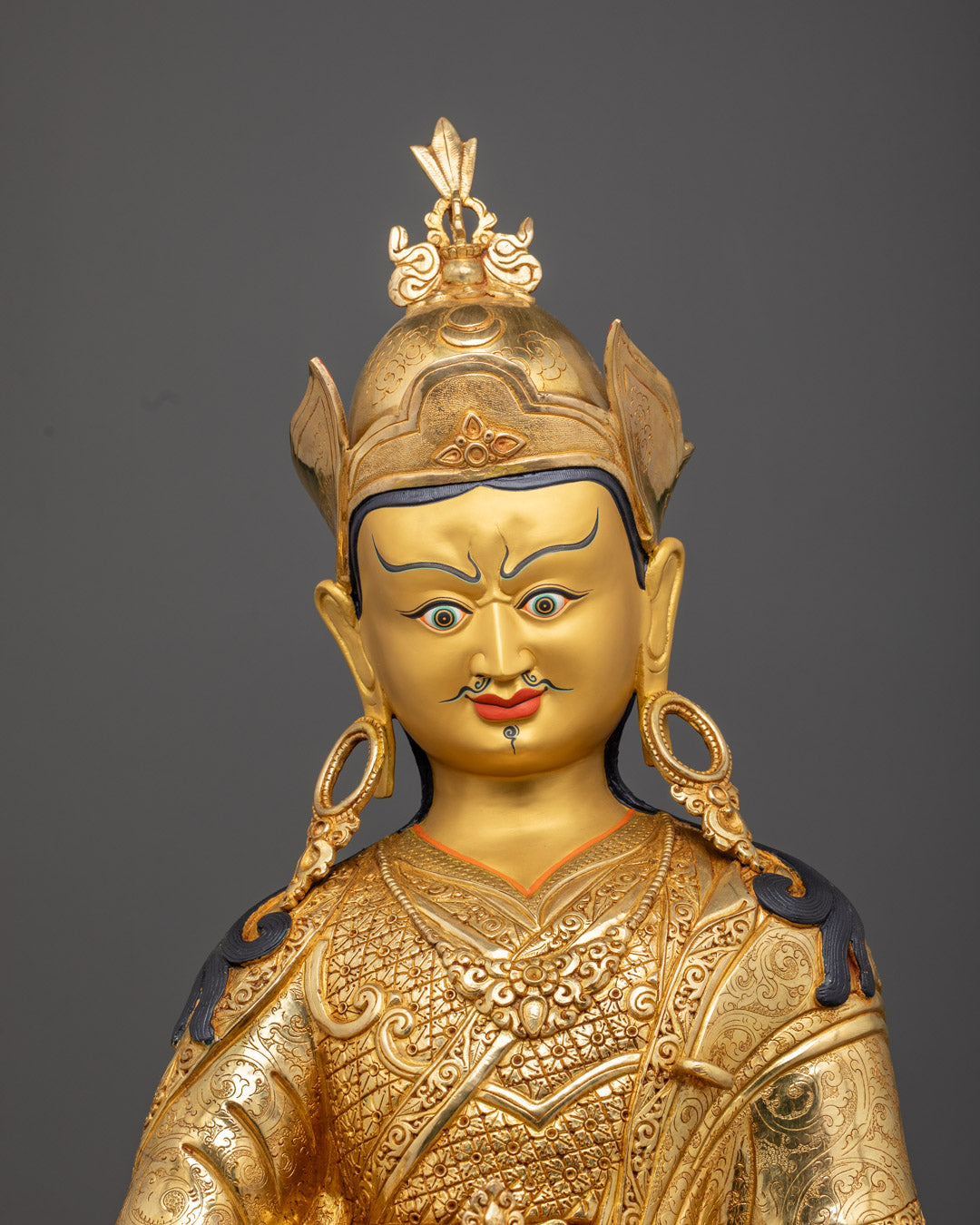 Guru Rinpoche’s serene face with third-eye detail, showcasing intricate gold gilding and acrylic color shading.