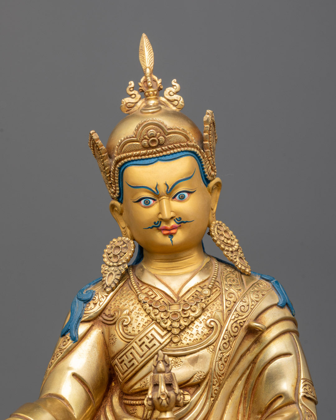 Close-up of Guru Rinpoche’s serene facial expression with traditional lotus hat