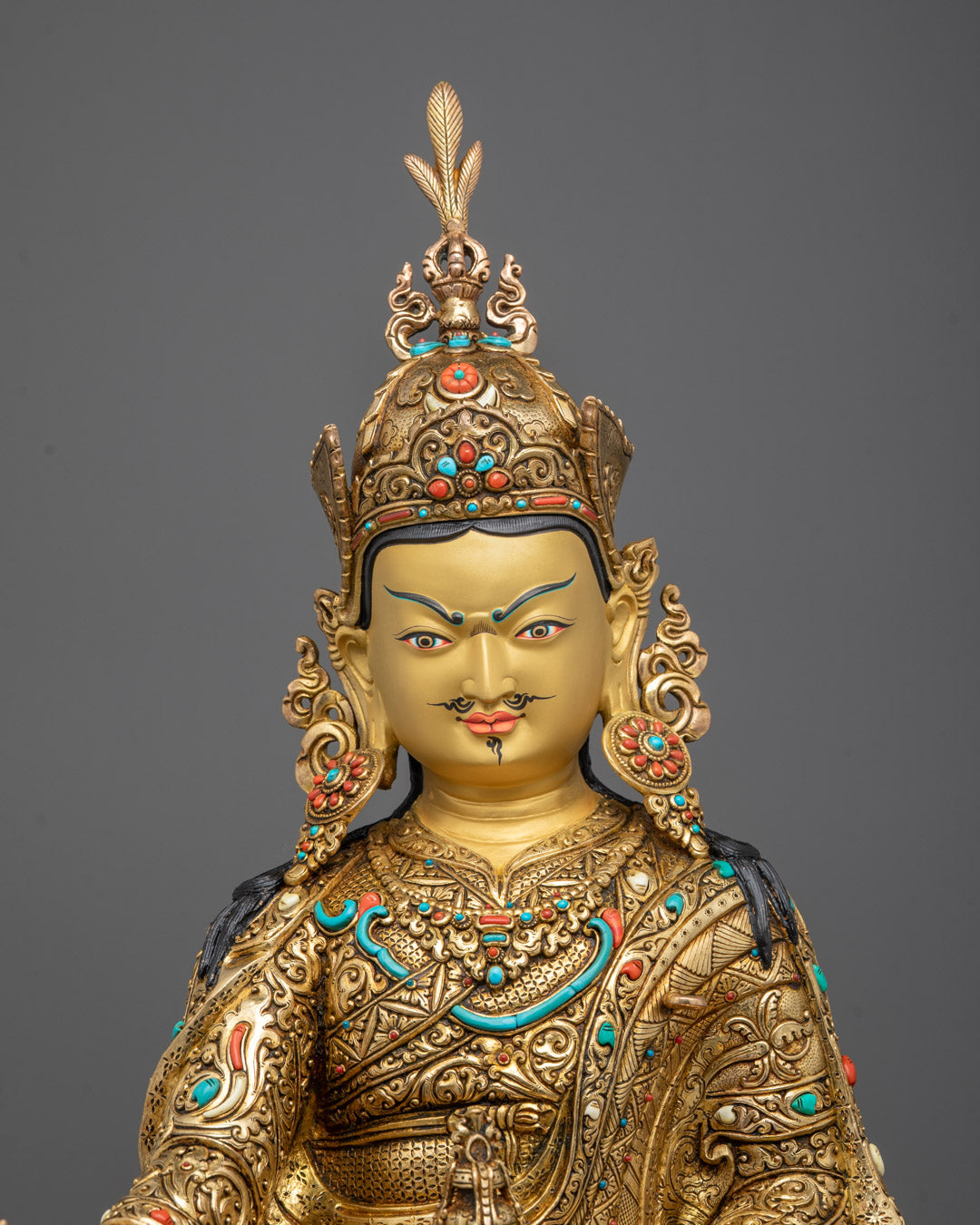Close-up of Guru Rinpoche’s serene gold-gilded face and intricate crown