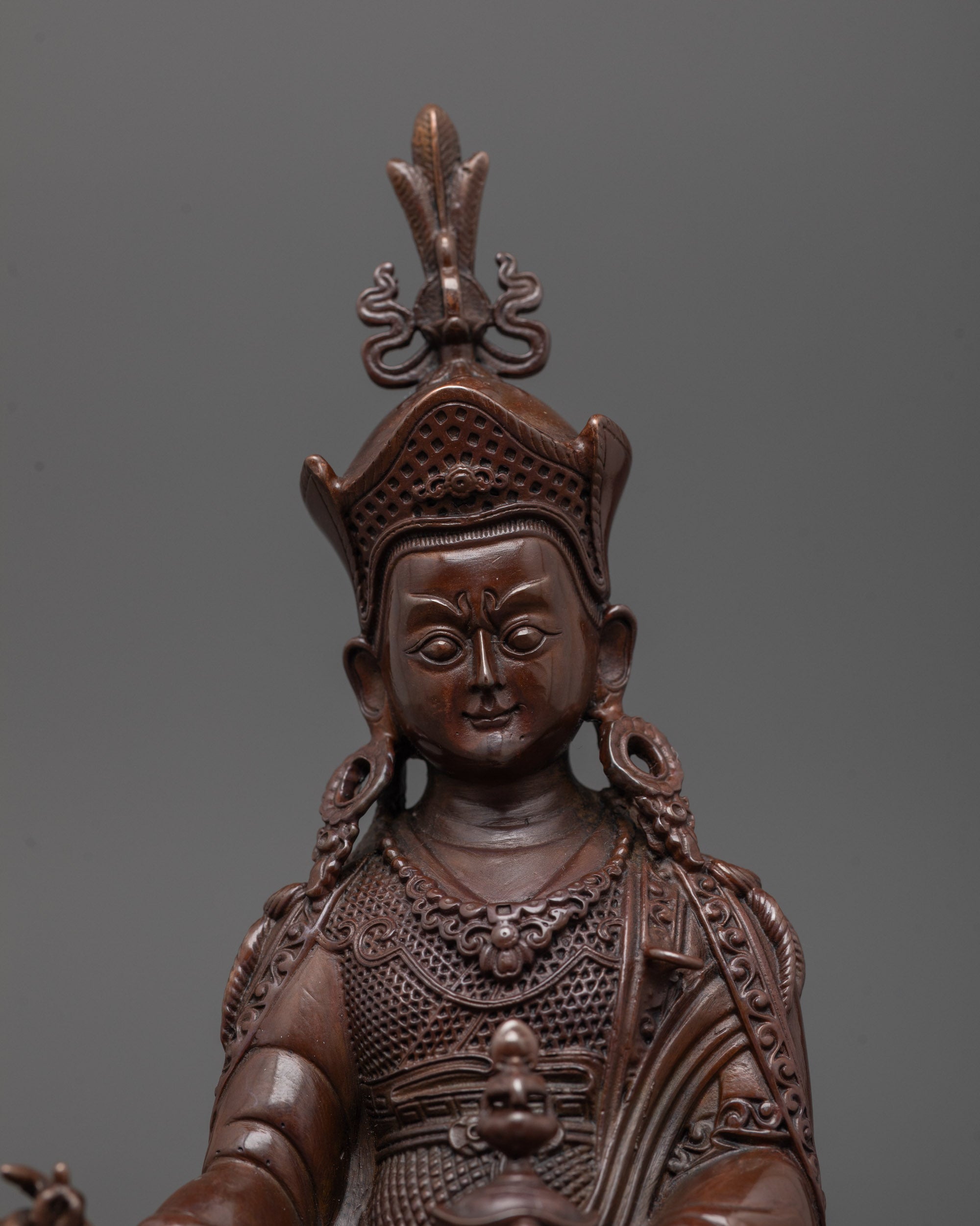 Close-up of Padmasambhava statue showing oxidized copper face and khatvanga trident