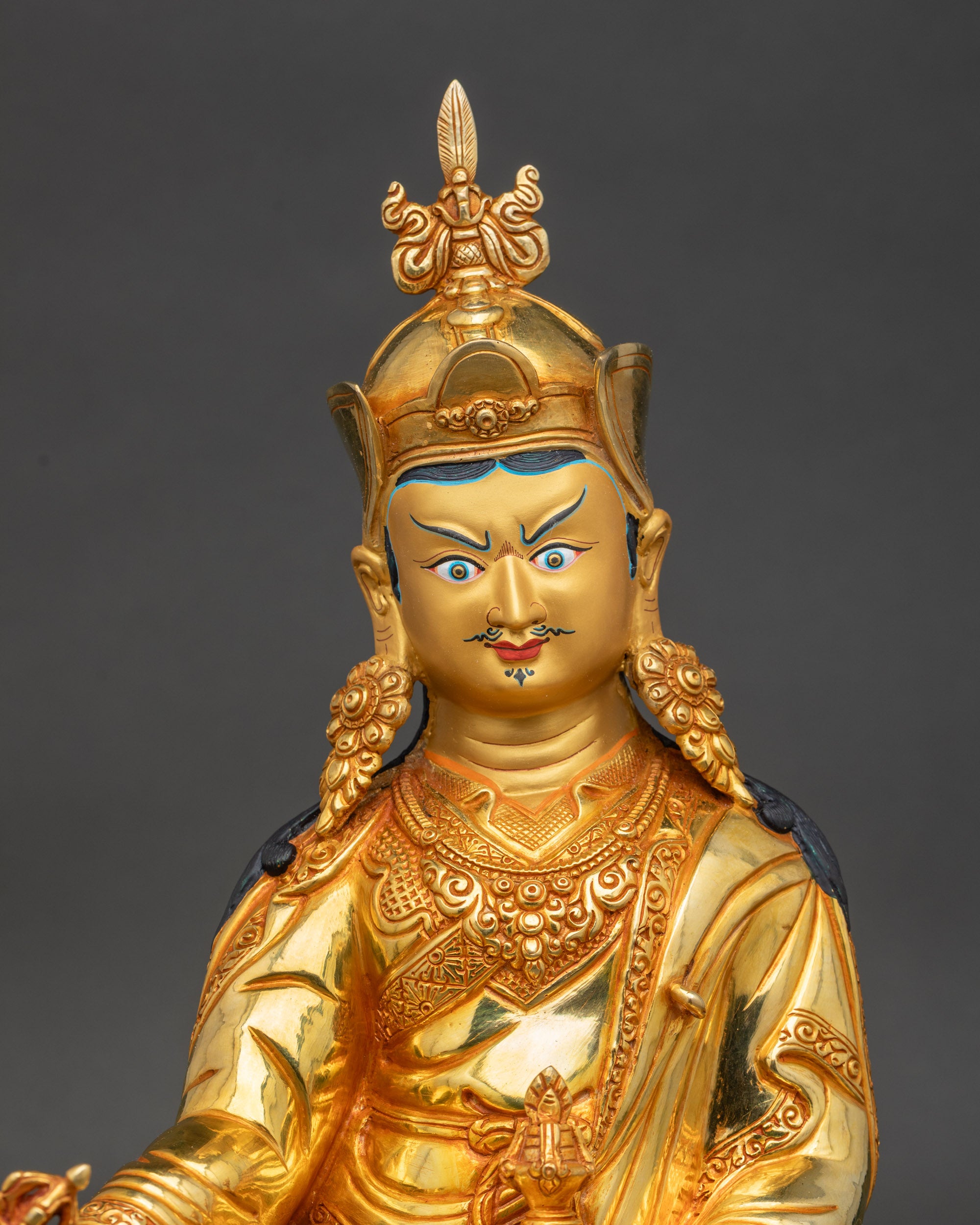 Close-up of Guru Rinpoche statue showing detailed carvings on robes and intricate motifs