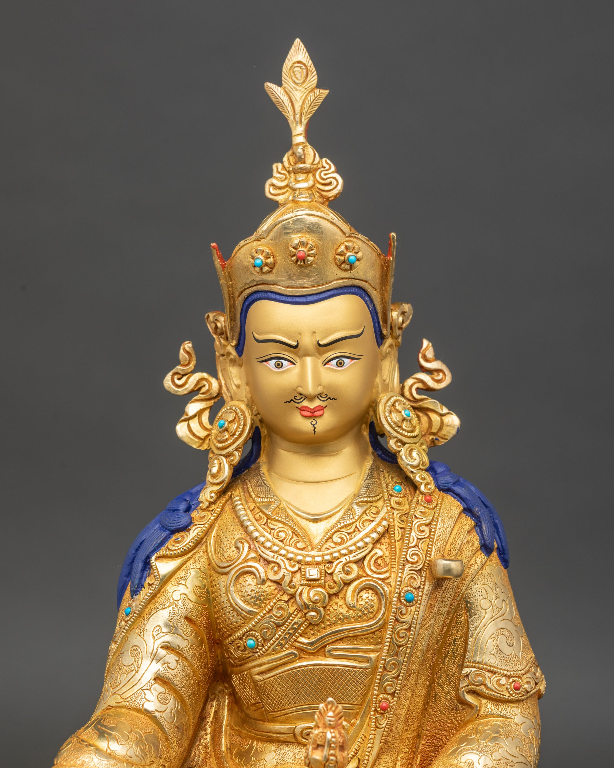Close-up of Guru Rinpoche statue showing ornate lotus base and intricate gold detailing