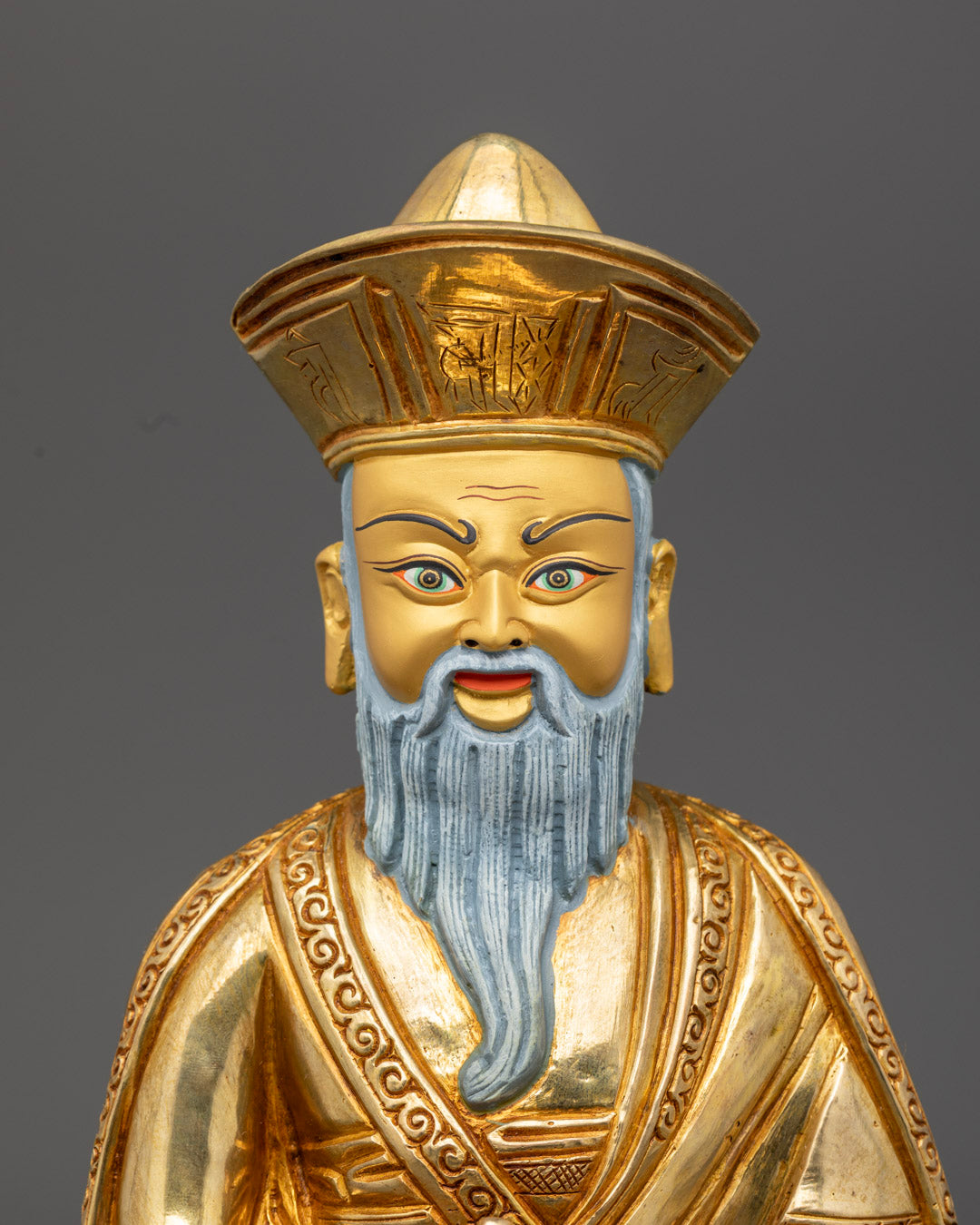 Guru Shapdum’s face with serene expression and vibrant hand-painted colors on traditional Tibetan statue.