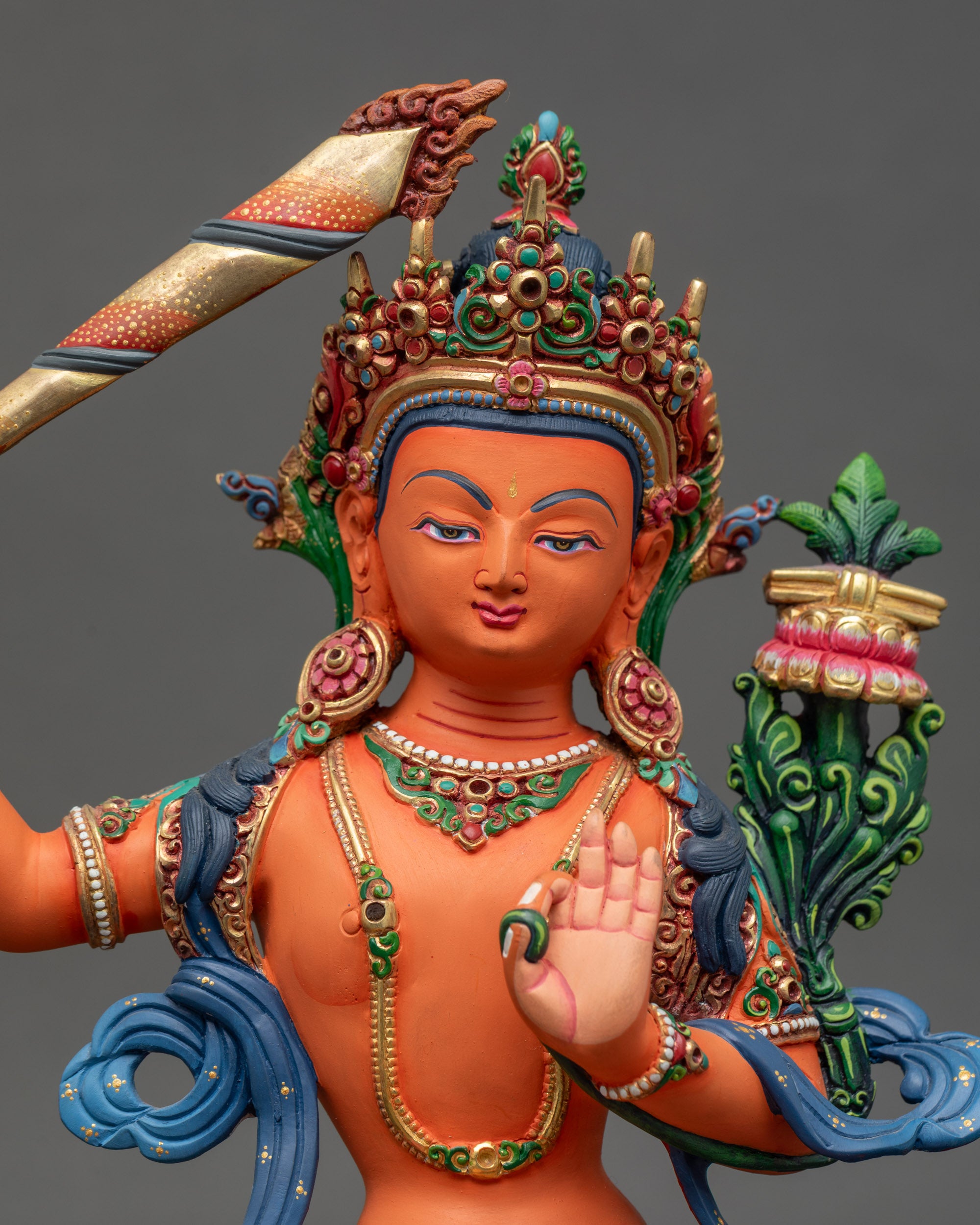 Close-up of Manjushri statue face and vibrant acrylic details, seated on lotus throne