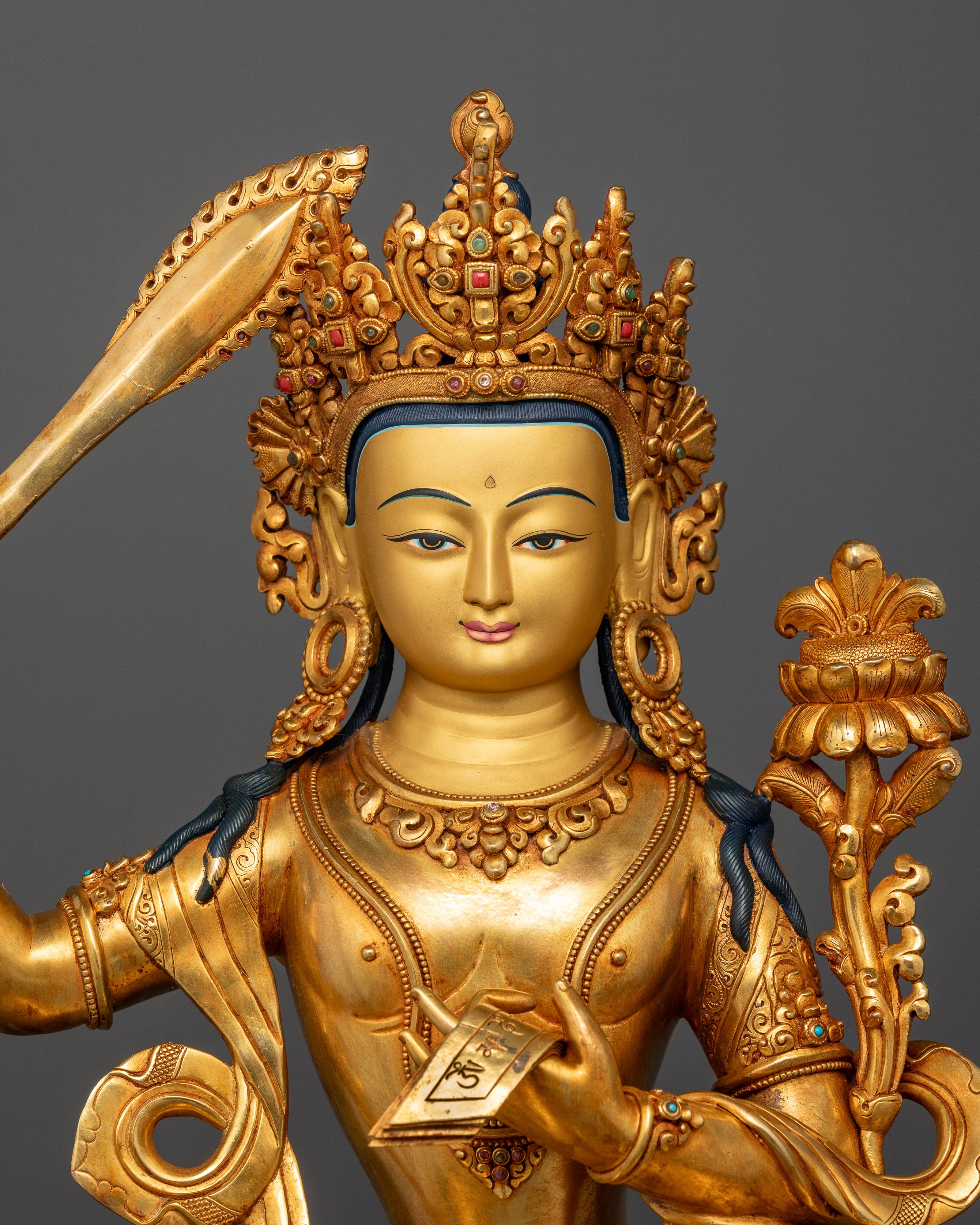 Close-up of Manjushri statue face with 24K gold-painted features and serene expression