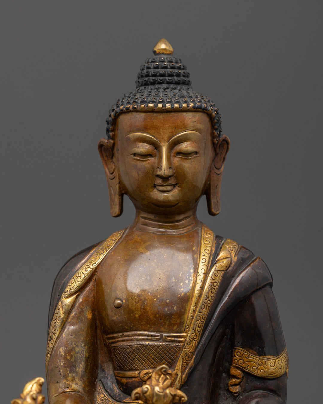 Close-up of Medicine Buddha’s gold-plated hands holding the healing myrobalan fruit