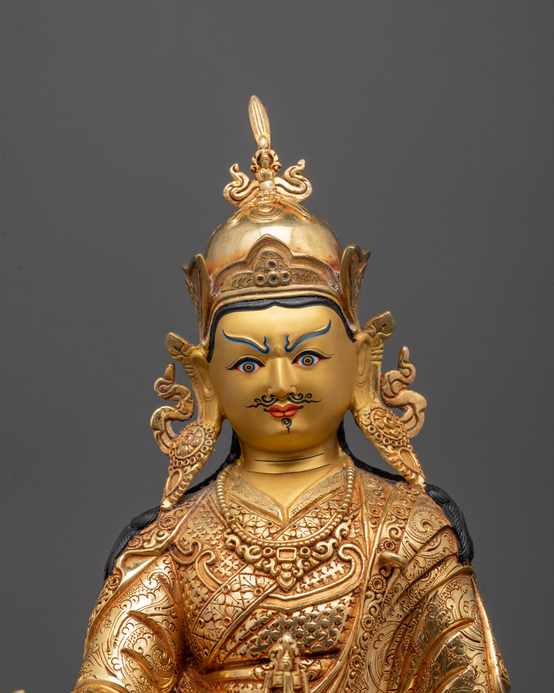 Close-up of Padmasambhava’s gold-gilded face and detailed lotus tiara