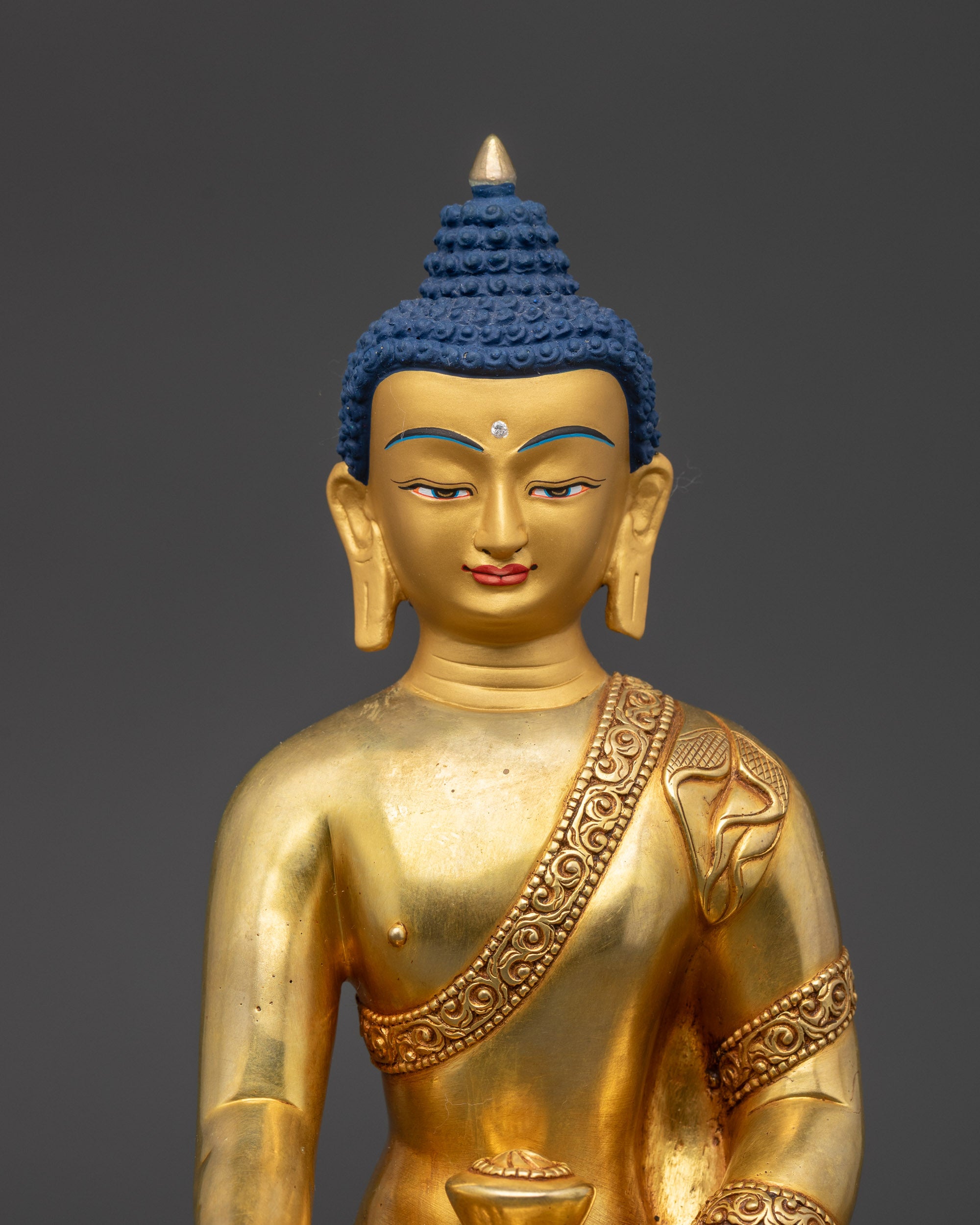 Close-up of Shakyamuni Buddha statue face and intricate carved monk's robe