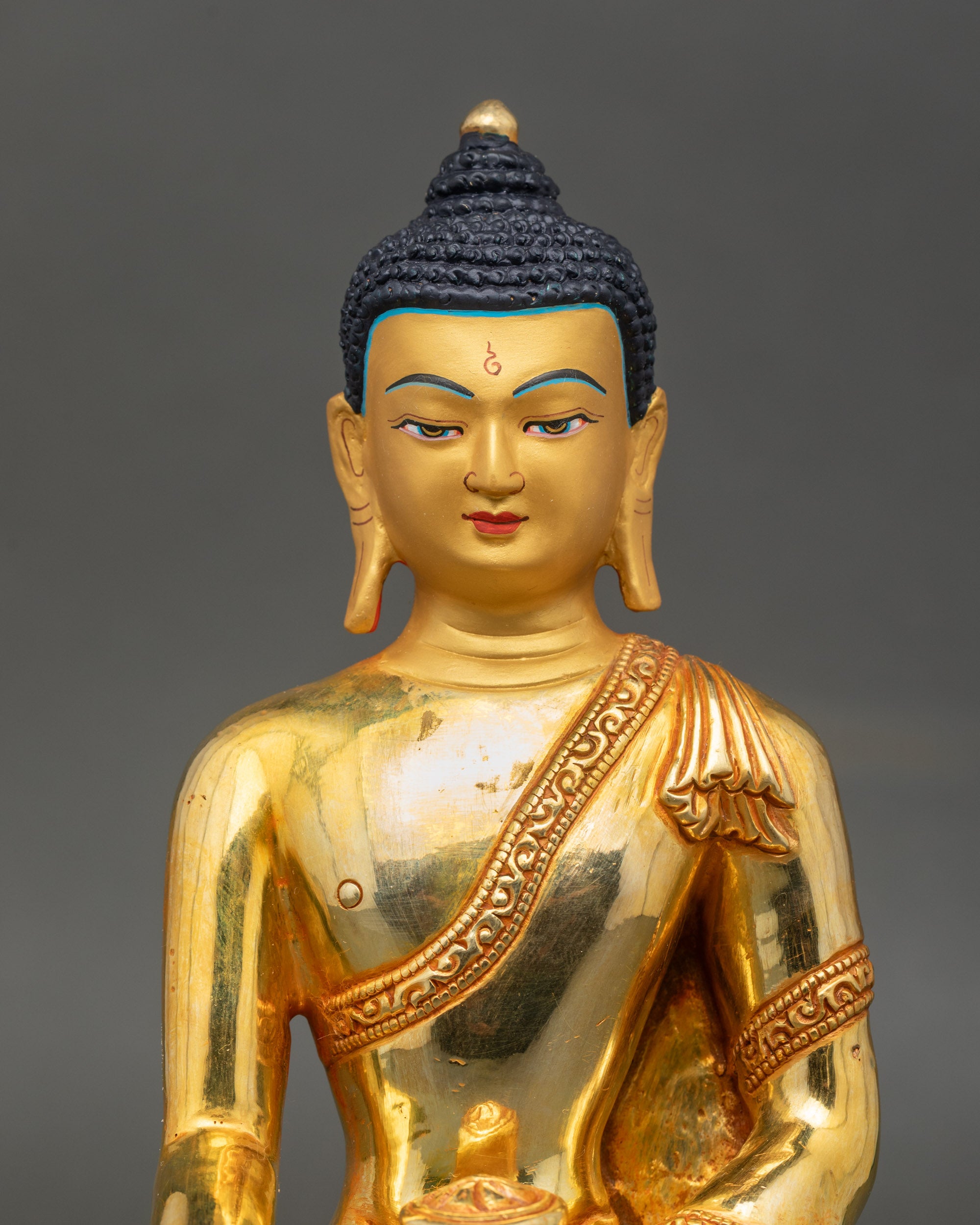 Close-up of Shakyamuni Buddha statue face with gold paint, showing serene and compassionate expression
