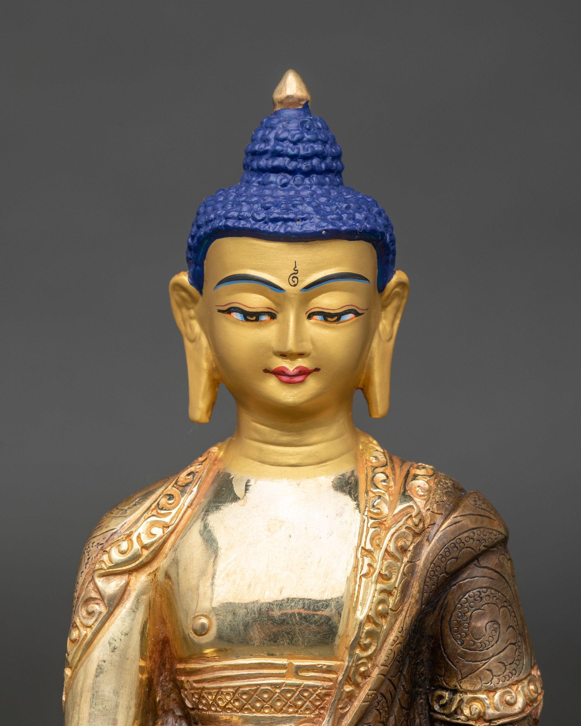 Close-up of Shakyamuni Buddha statue showing 24k gold-painted face and intricate details