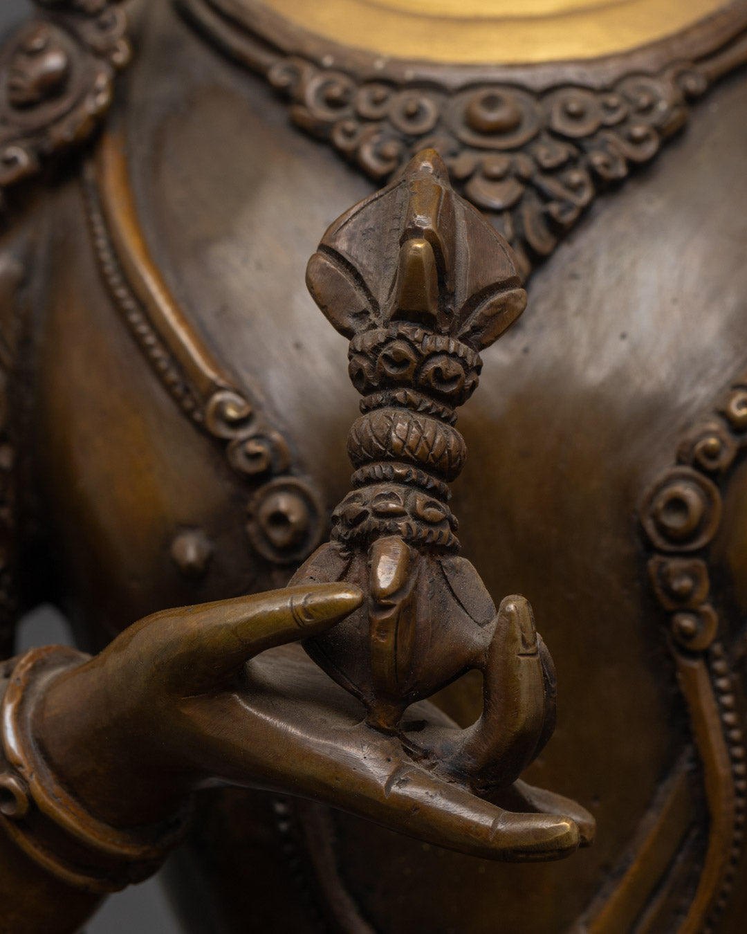 Close-up of Vajrasattva statue's oxidized copper torso showing intricate craftsmanship and patina texture
