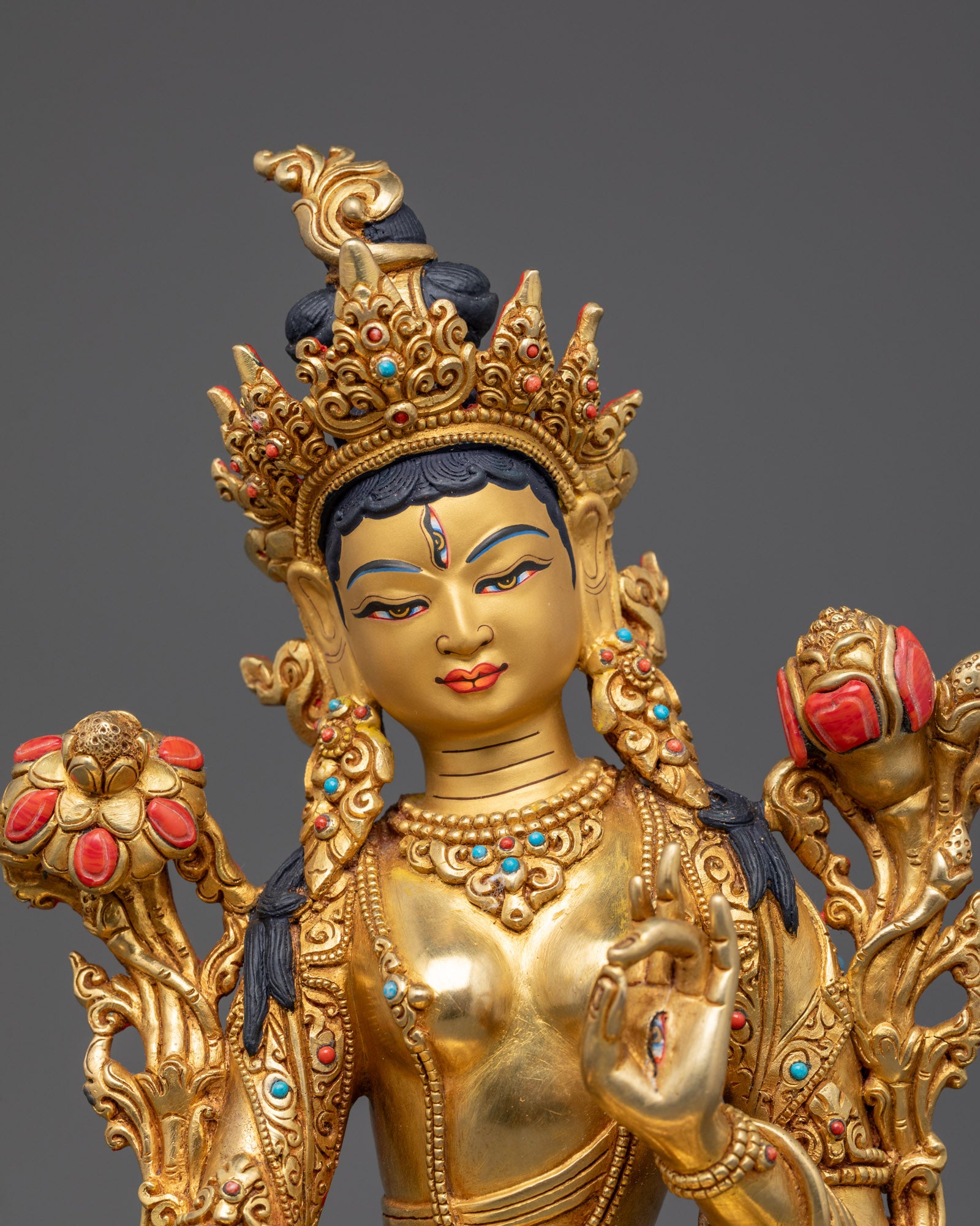 White Tara’s serene face showing seven eyes symbolizing compassion and wisdom on a gold-gilded copper statue.