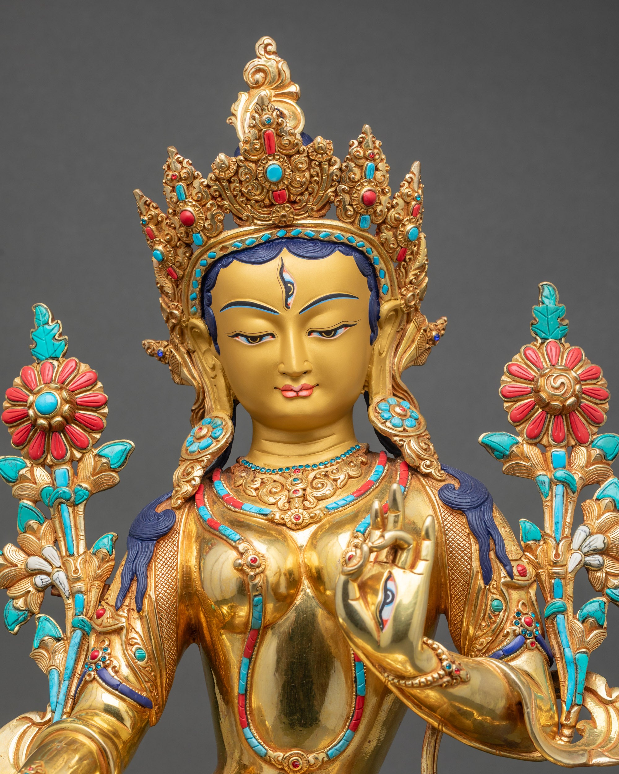 Close-up of White Tara sculpture, detailed hand-painted floral halo and serene gold face