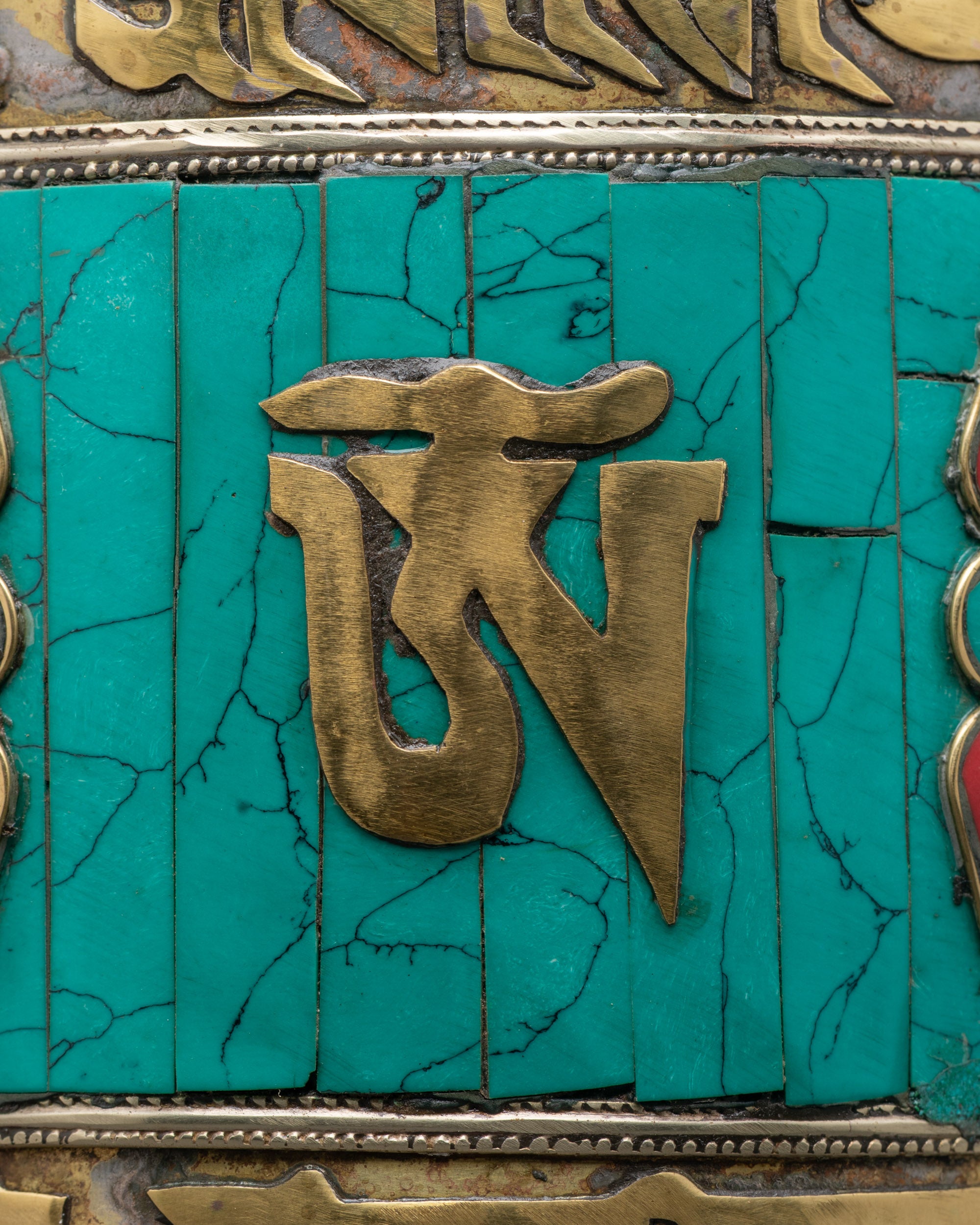 Close-up of engraved mantras and turquoise stones on Tibetan Prayer Wheel