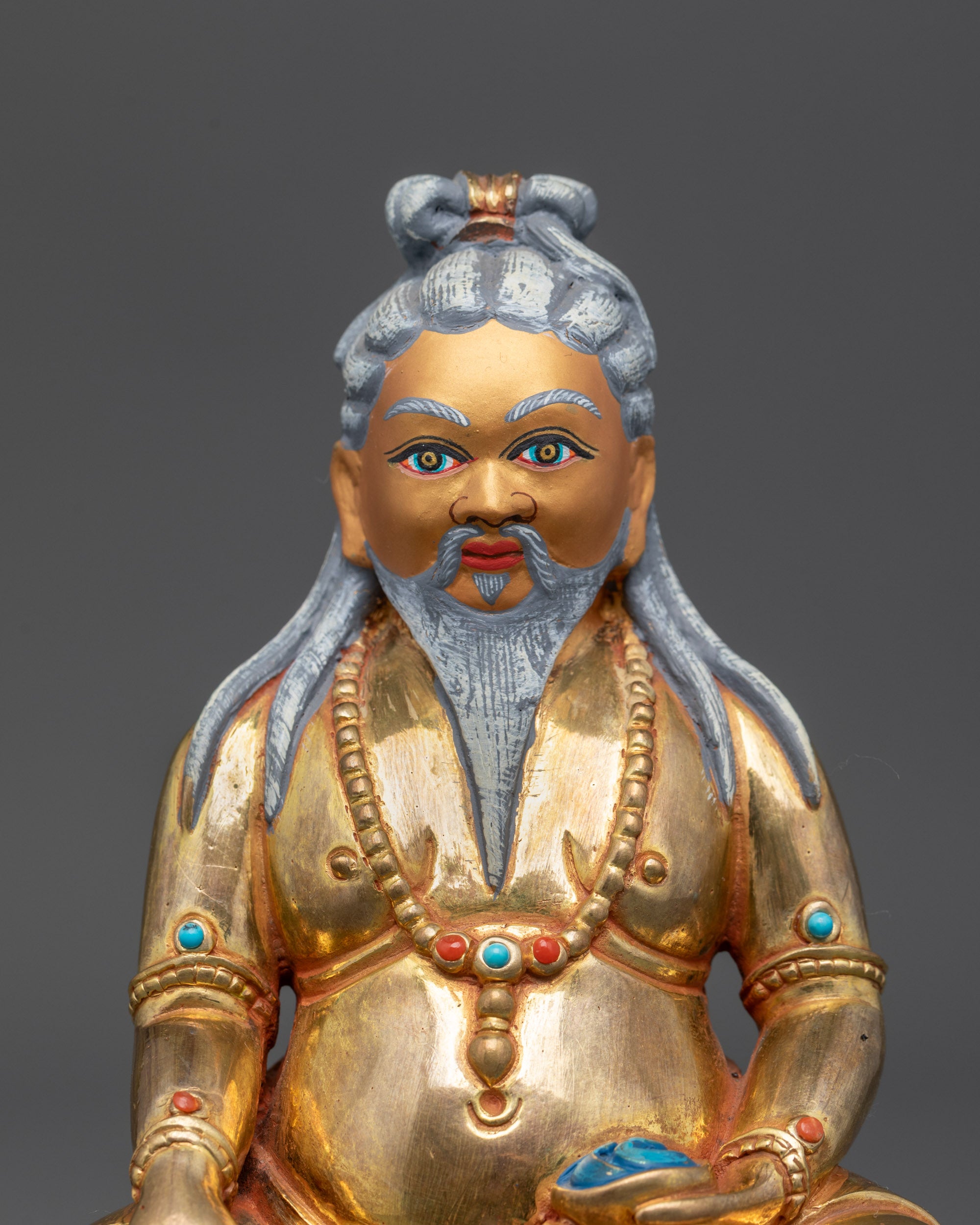 Close-up of gold-gilded face and detailed jewelry of Thang Tong Gyalpo Statue