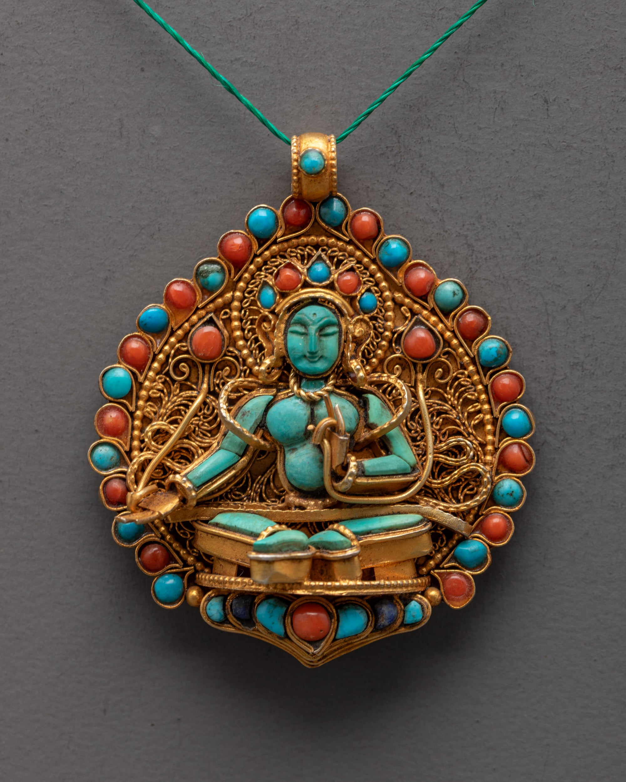 Close-up of hand-carved Green Tara centerpiece on gold-gilded locket with semi-precious stones