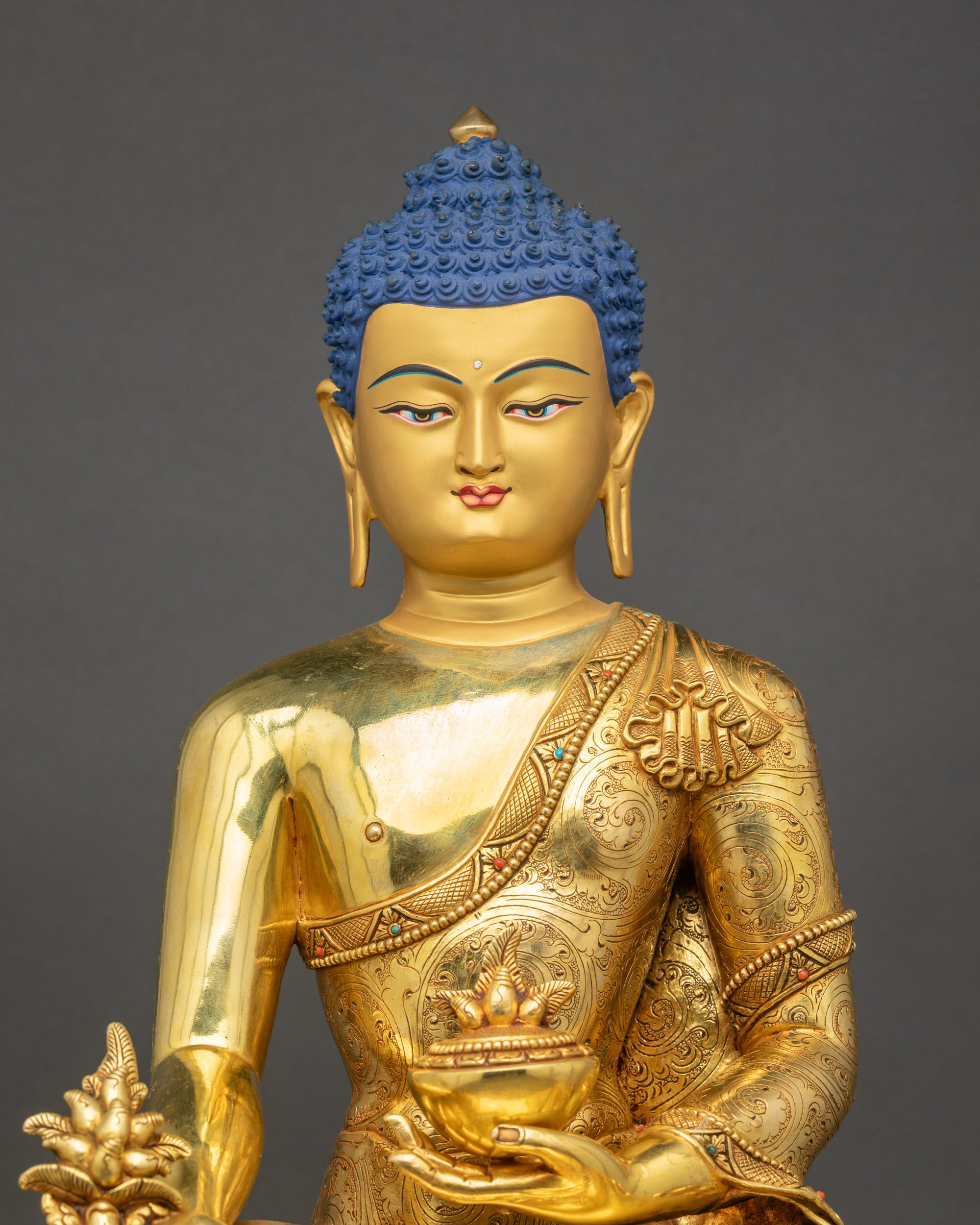 Close-up of handcrafted Medicine Buddha showing gold fire-gilded details and robe carvings