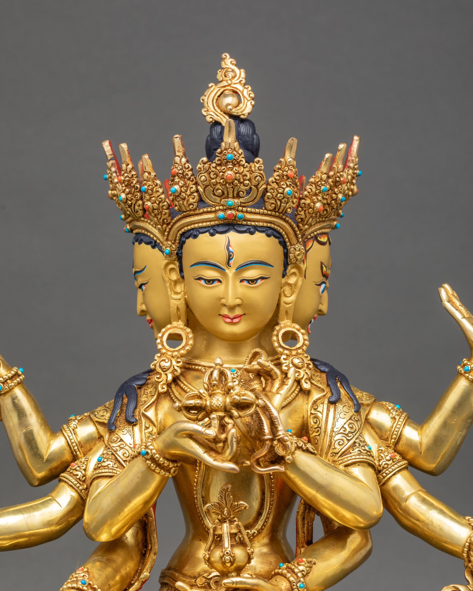 Close-up of handcrafted Namgyalma deity holding sacred vase, vishva dorje, and bow in copper hands