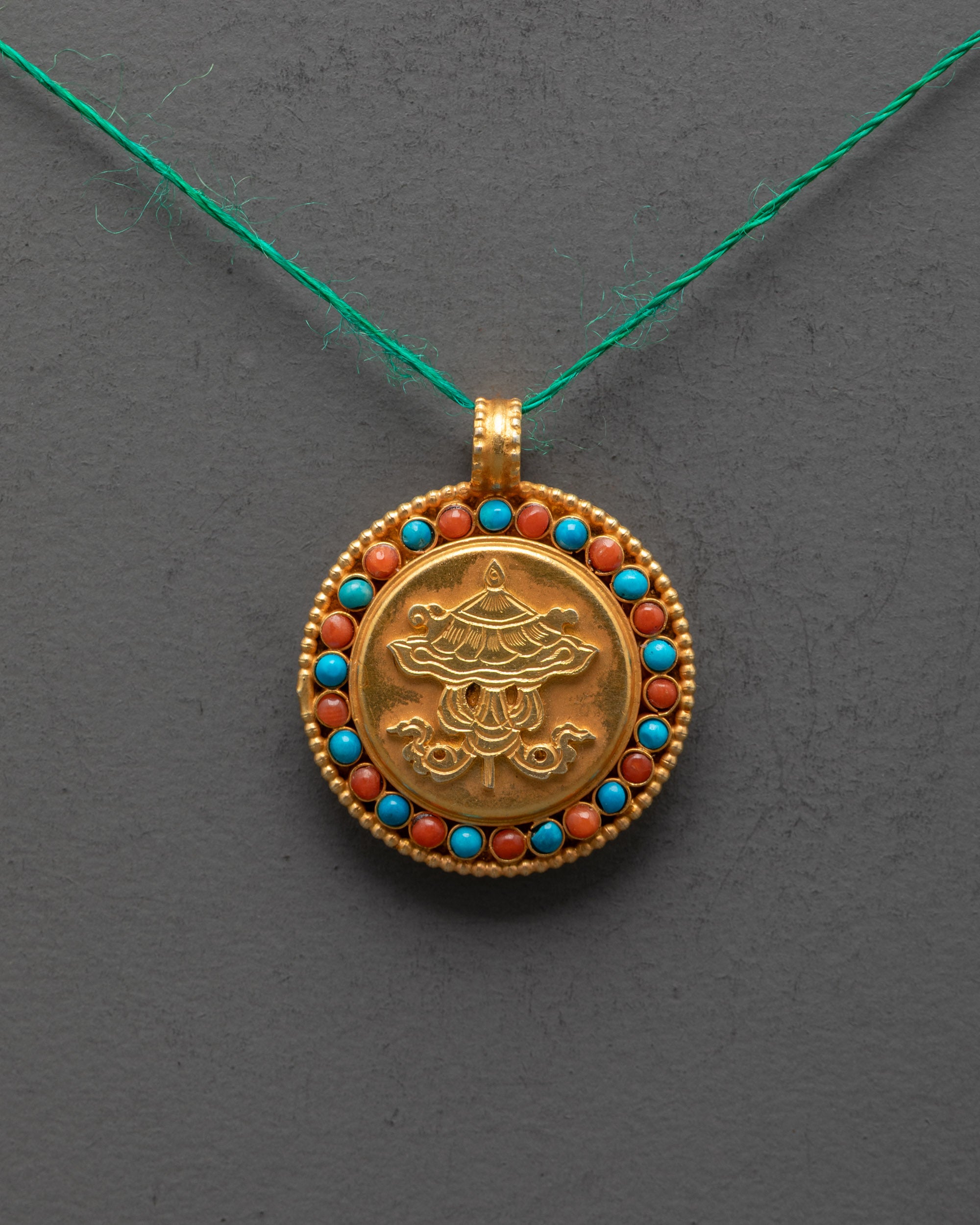 Close-up of intricate Victory Banner design on gold-plated copper pendant with stone details