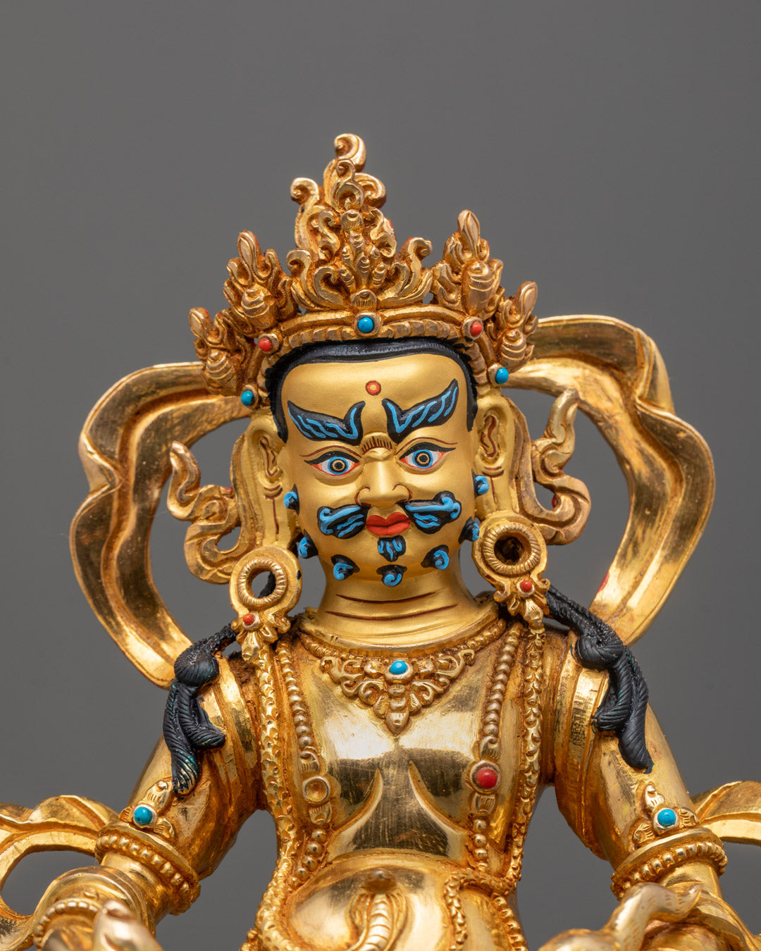 Close-up of intricate carvings and semi-precious stones on Dzambhala Tibetan wealth sculpture