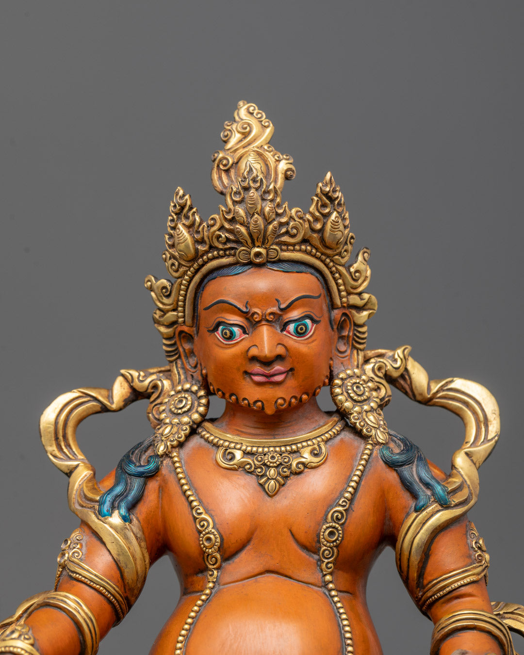 Close-up of intricate carvings on crown, jewelry, and flowing robes of Dzambhala Sculpture