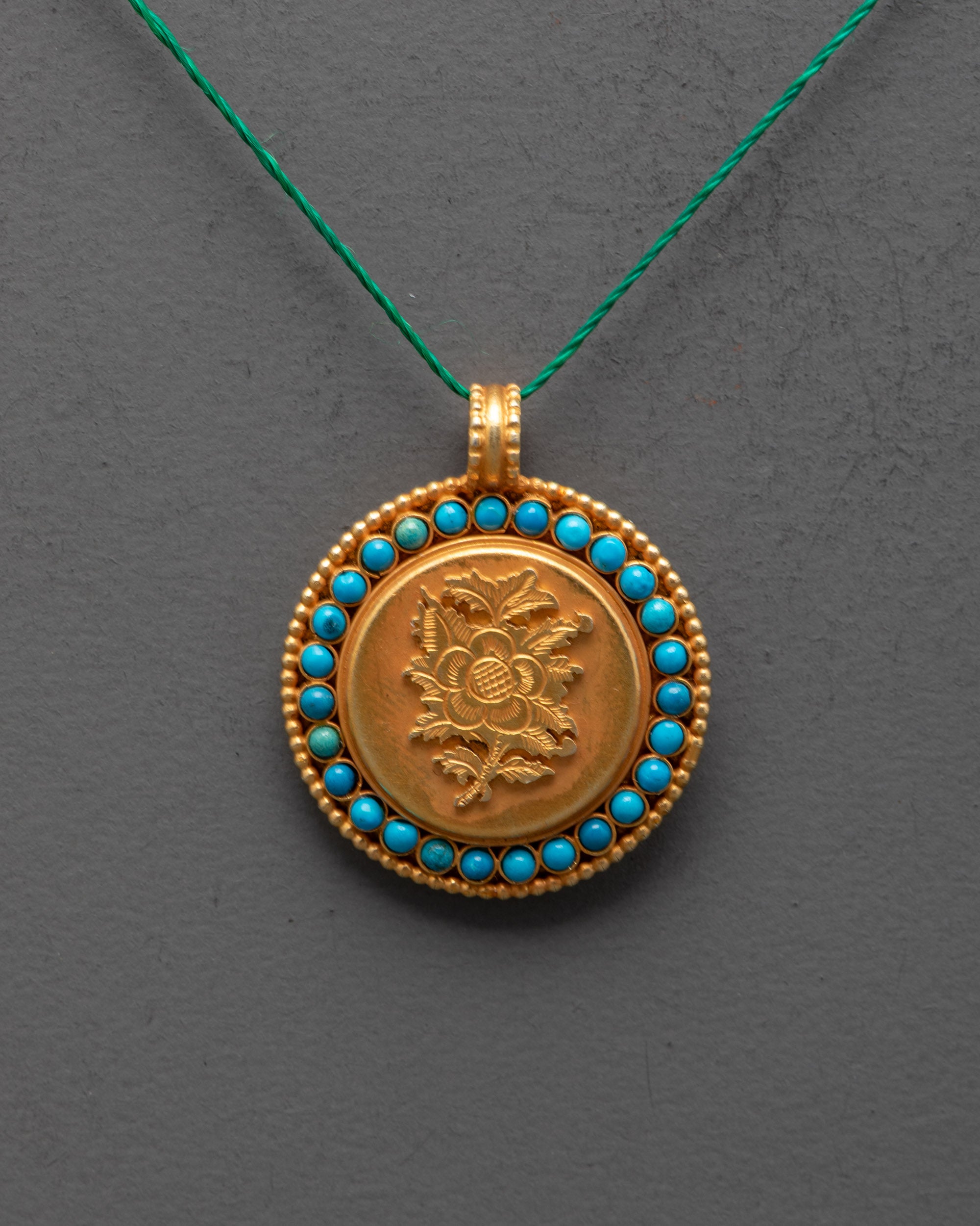 Close-up of intricate lotus design on gold-plated copper locket with gemstone accents