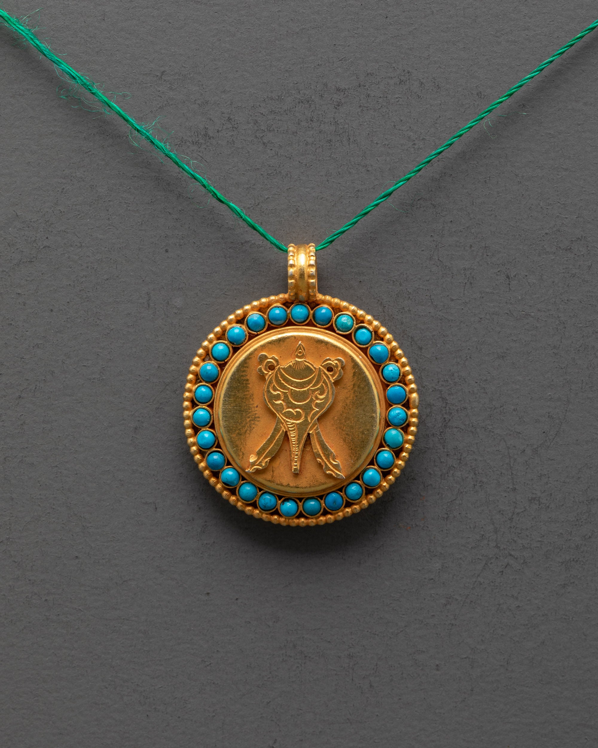 Close-up of intricate shell design on gold-plated copper locket with stone details
