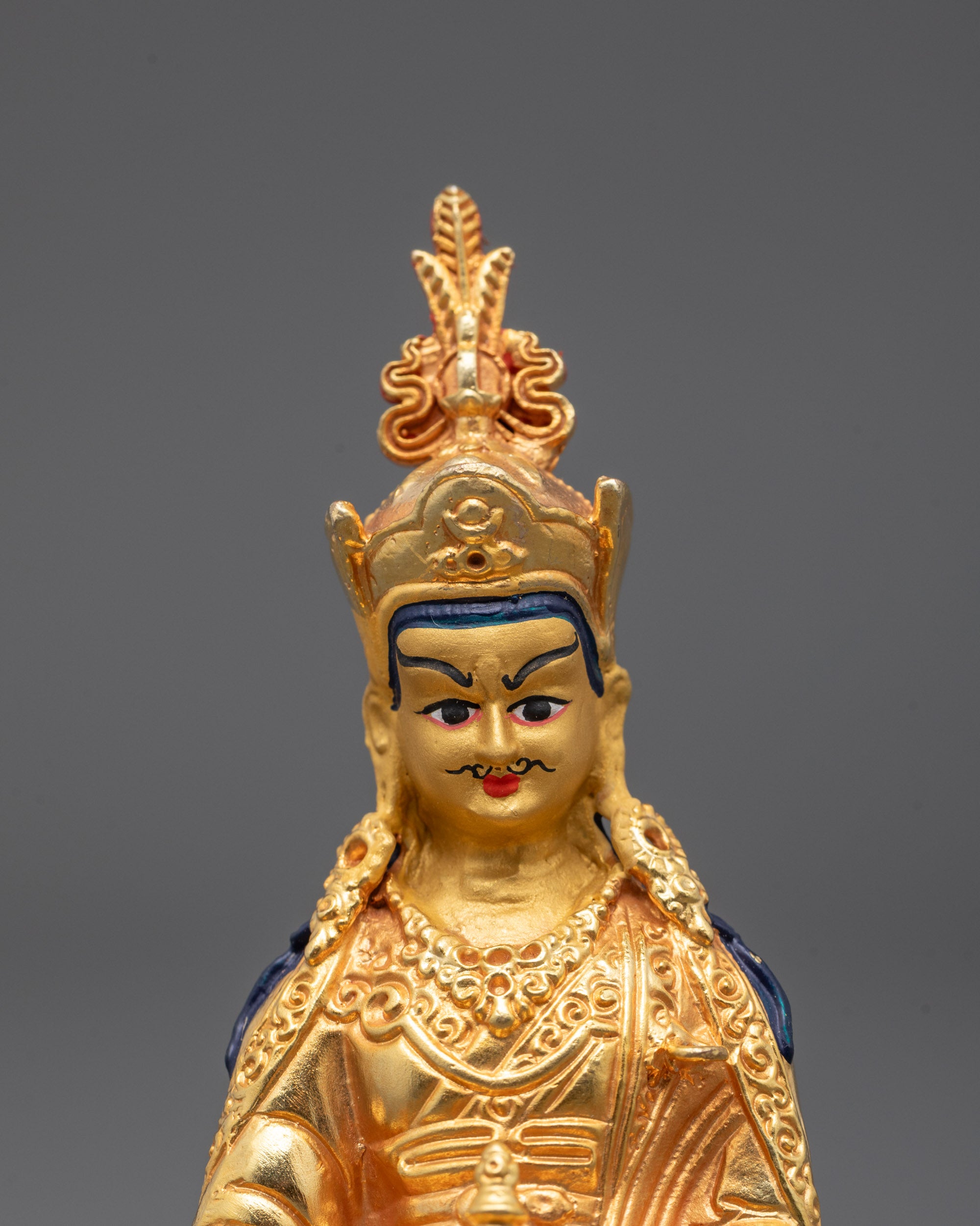 Close-up of intricately detailed face of Guru Rinpoche Buddha statue symbolizing protection