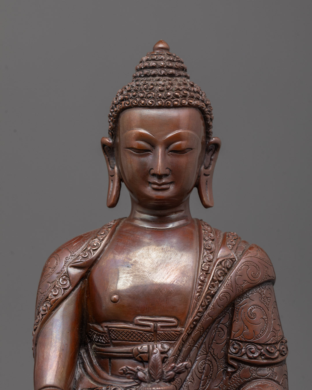 Close-up of oxidized copper face and intricate robe on Medicine Buddha statue
