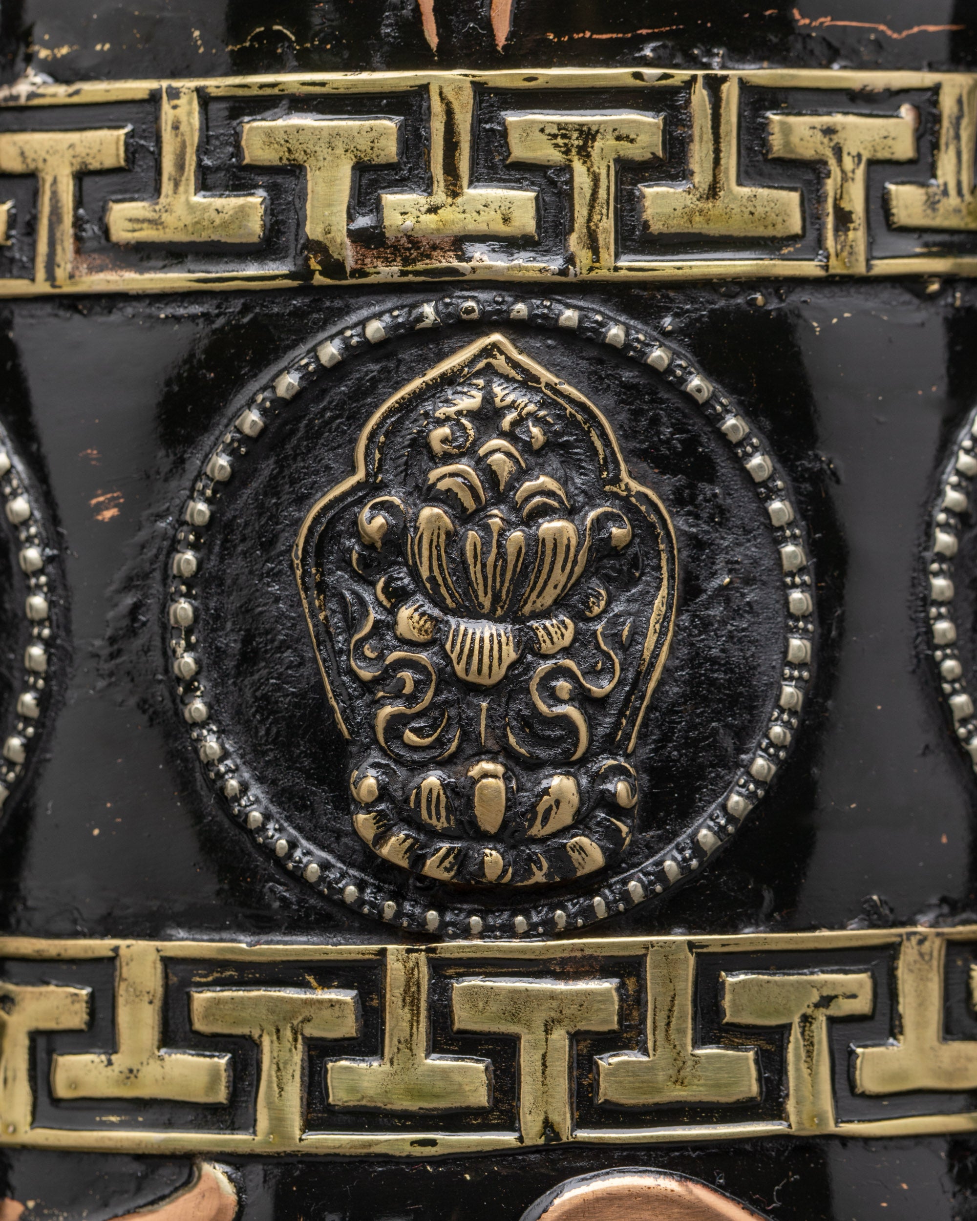 Close-up of prayer wheel with sacred mantras on copper base and white metal auspicious symbols
