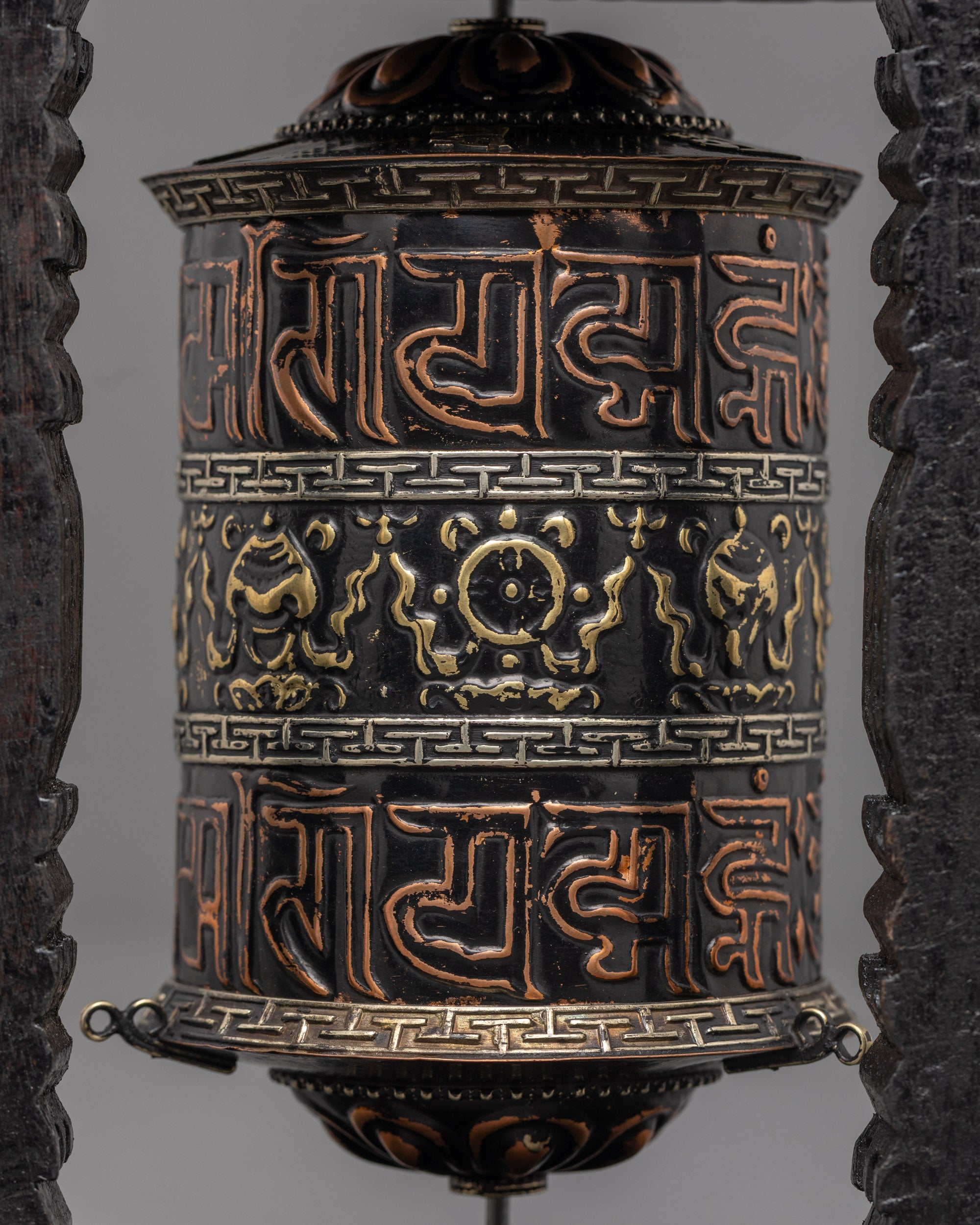 Close-up of sacred mantras on copper base of Tibetan prayer wheel with black acrylic paint