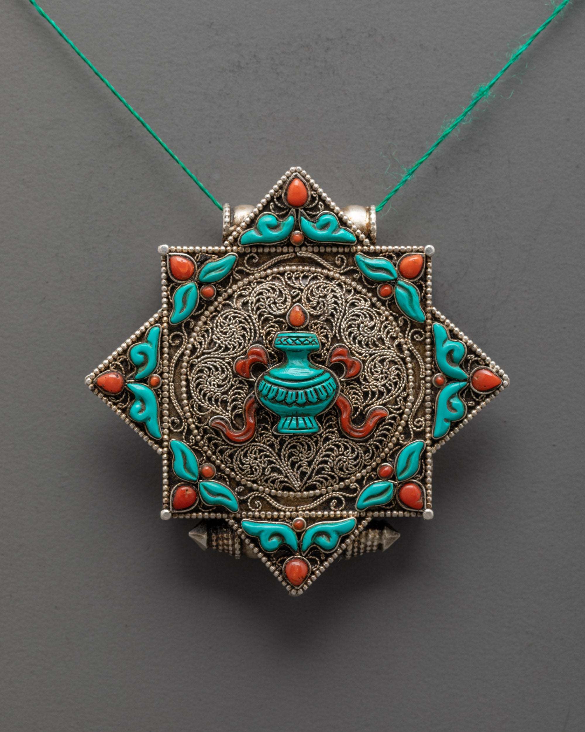 Close-up of turquoise Treasure Vase and intricate silver-plated filigree on handmade Nepalese locket